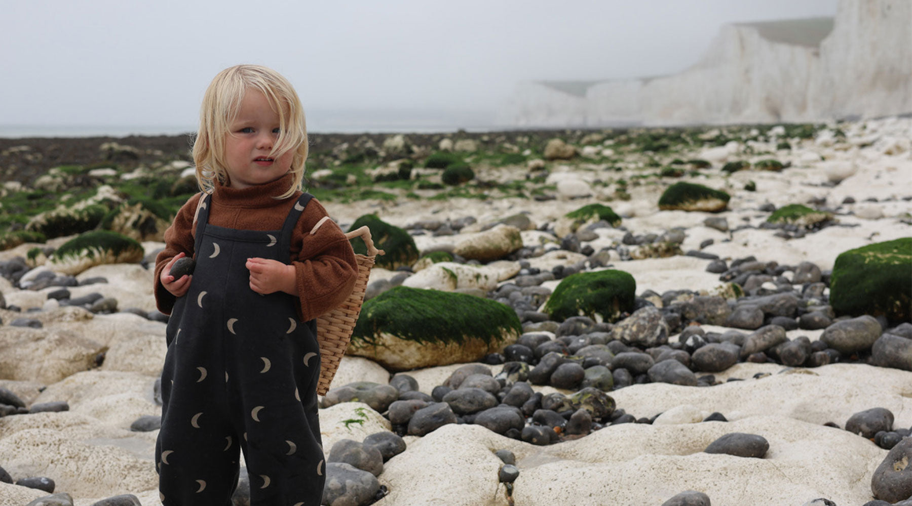 Toddler Wearing Brown Fleece Anorak & Charcoal Dungarees with Moon Print Carrying Basket