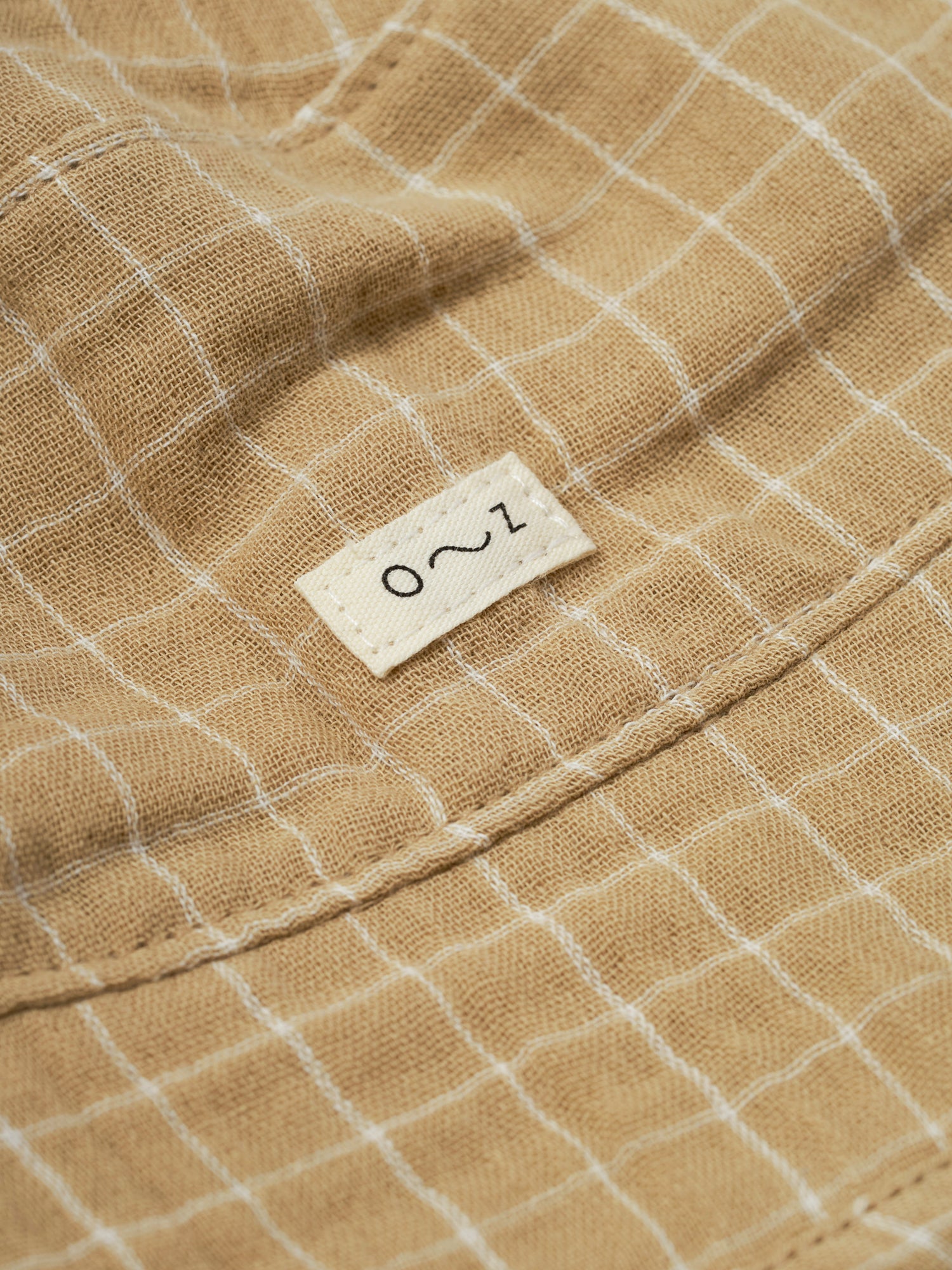 close up of baby and toddler gold grid check organic muslin bucket hat with chin ties