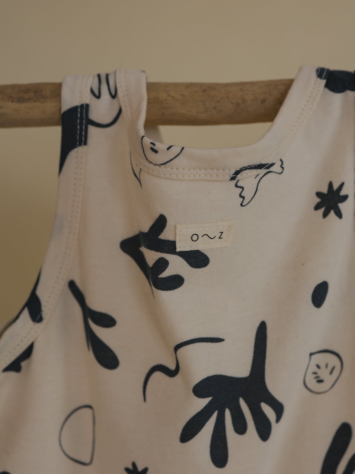 undyed cotton capri vest in white with navy ocean-inspired print & o~z label hanging on rod