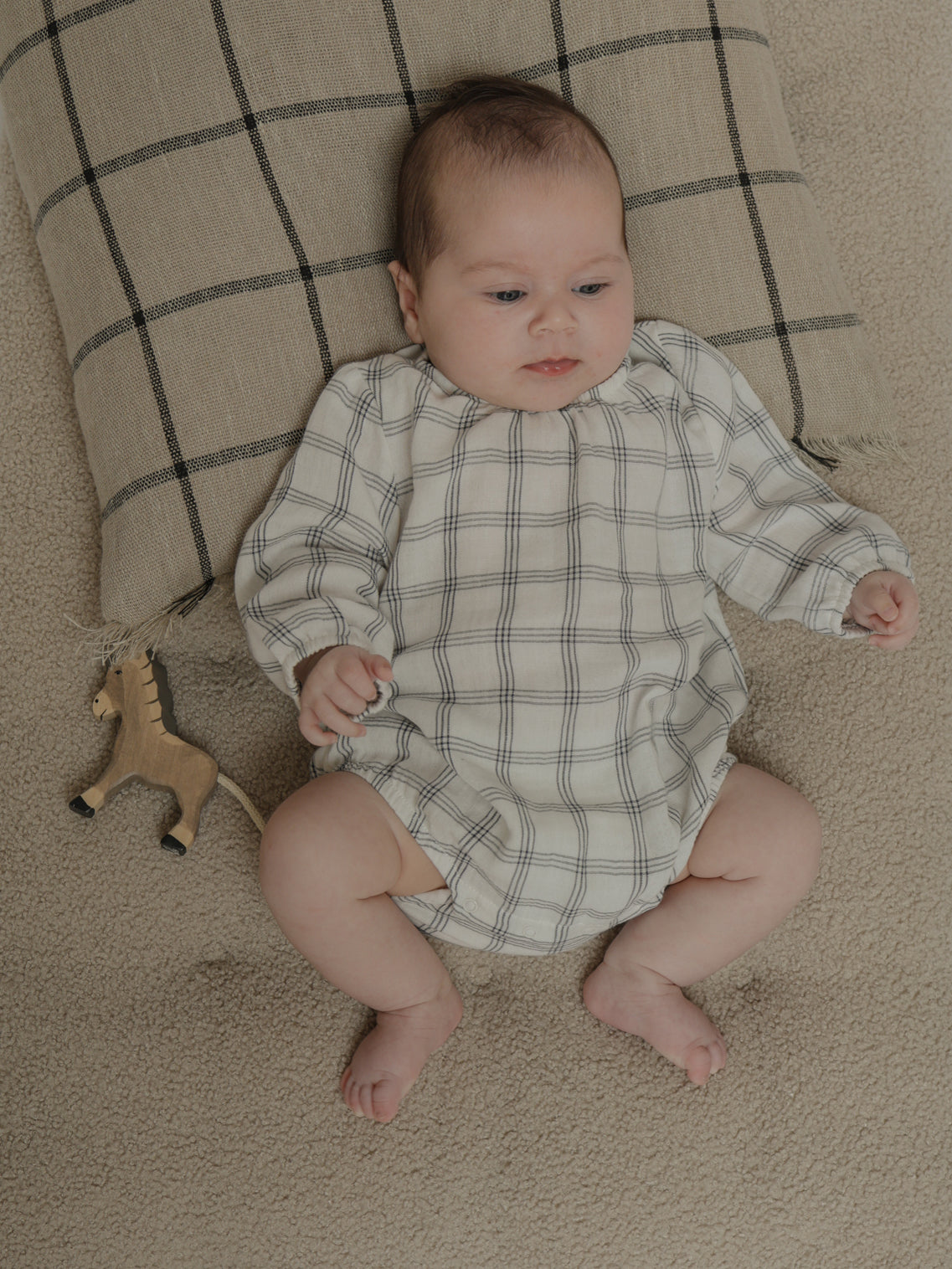 baby in white long sleeved window check bodysuit with gathered neckline & cuffs