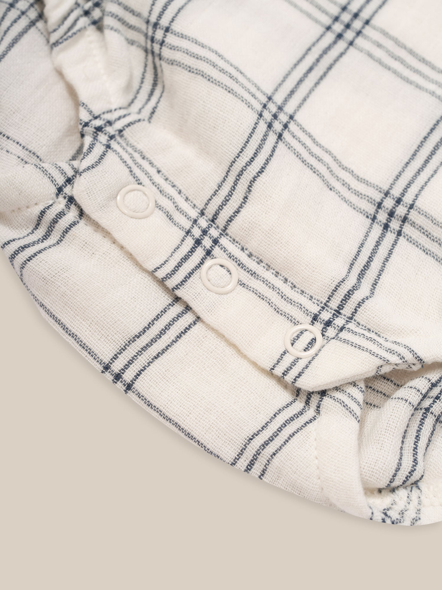 close up of baby window check long sleeved muslin bodysuit with gathered neckline & cuffs, crotch poppers