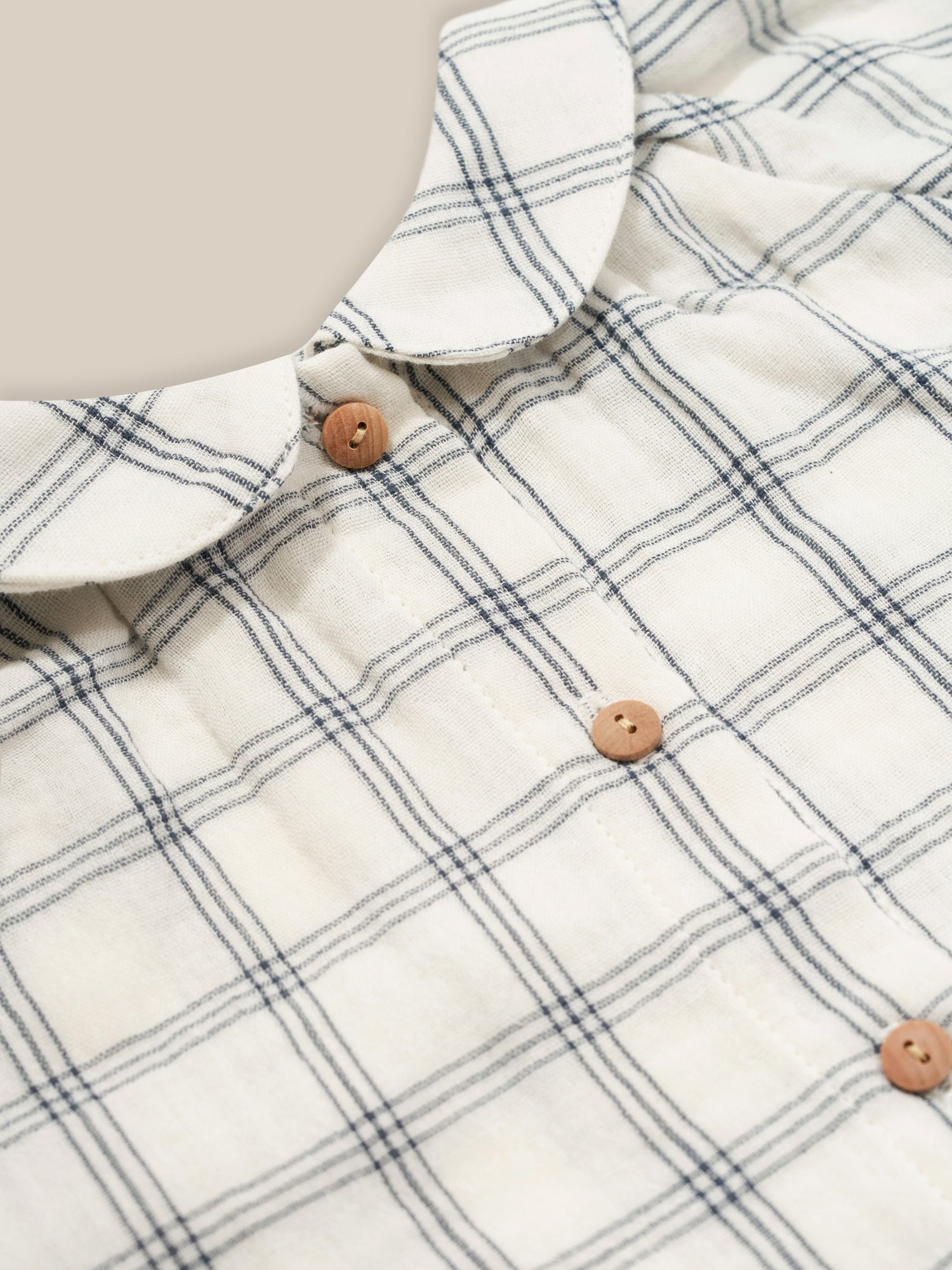 close up of baby navy window check long sleeved two-way muslin button-down white dress with peter pan collar