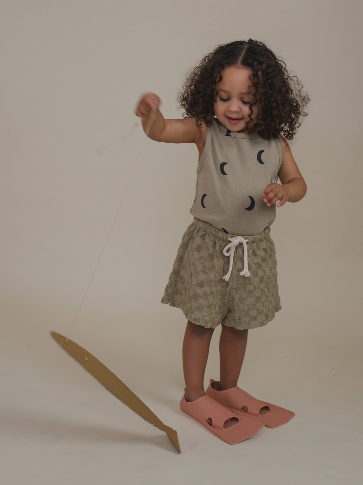 toddler wearing soft terry cotton rope shorts with checkerboard pattern pretend play fishing