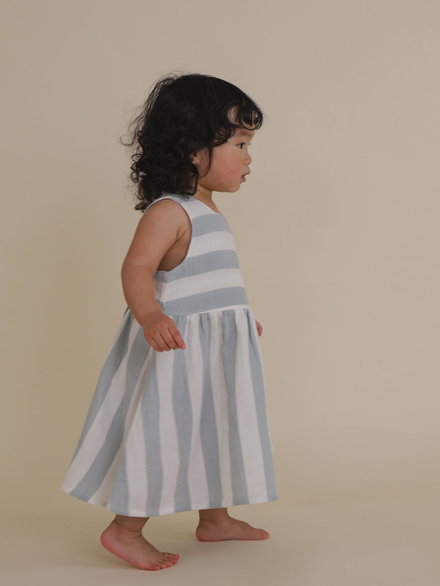 toddler walking in sardine blue striped muslin sleeveless dress with button back