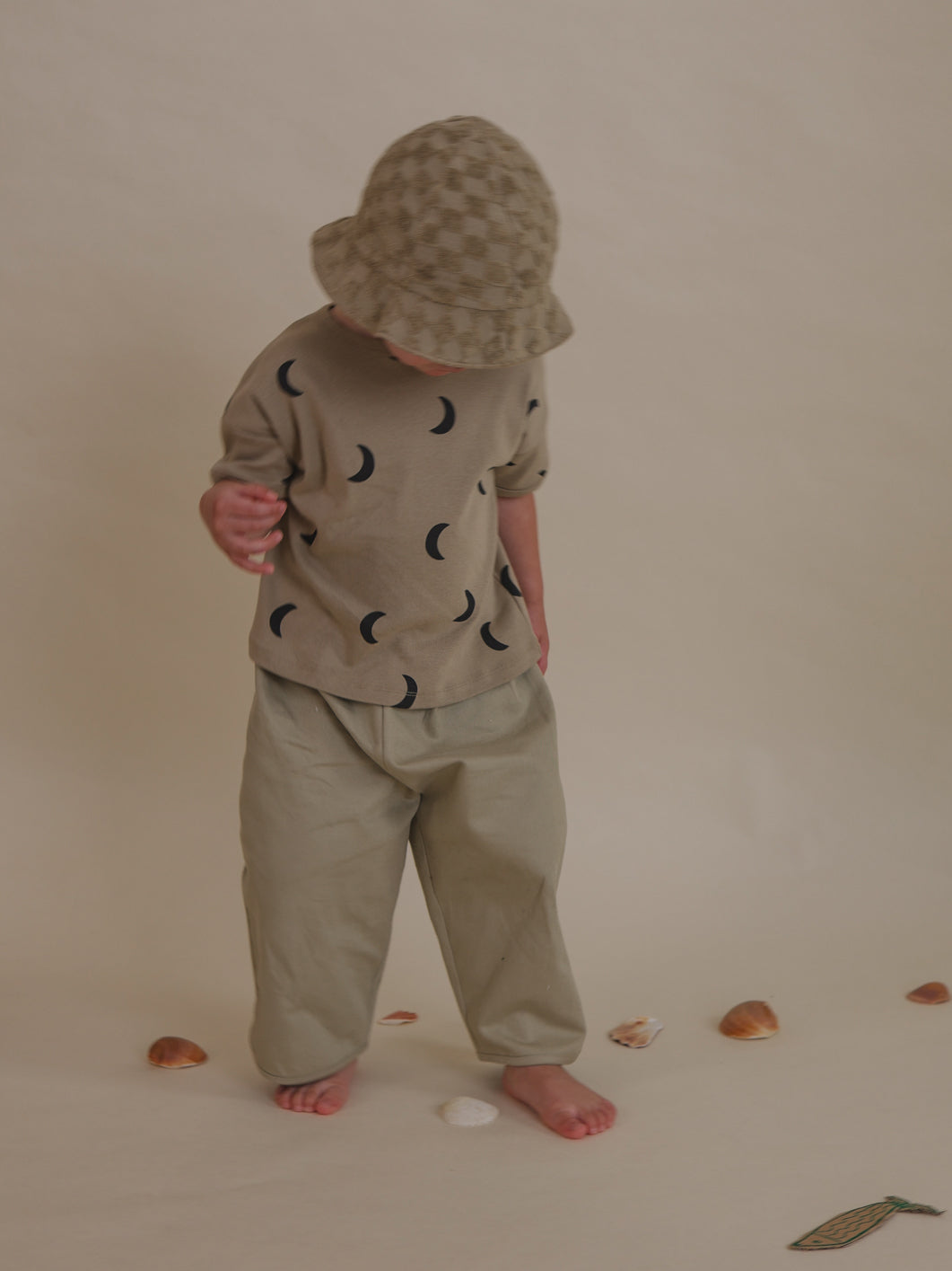 toddler wearing beige checkerboard organic terry cotton sun hat looking down