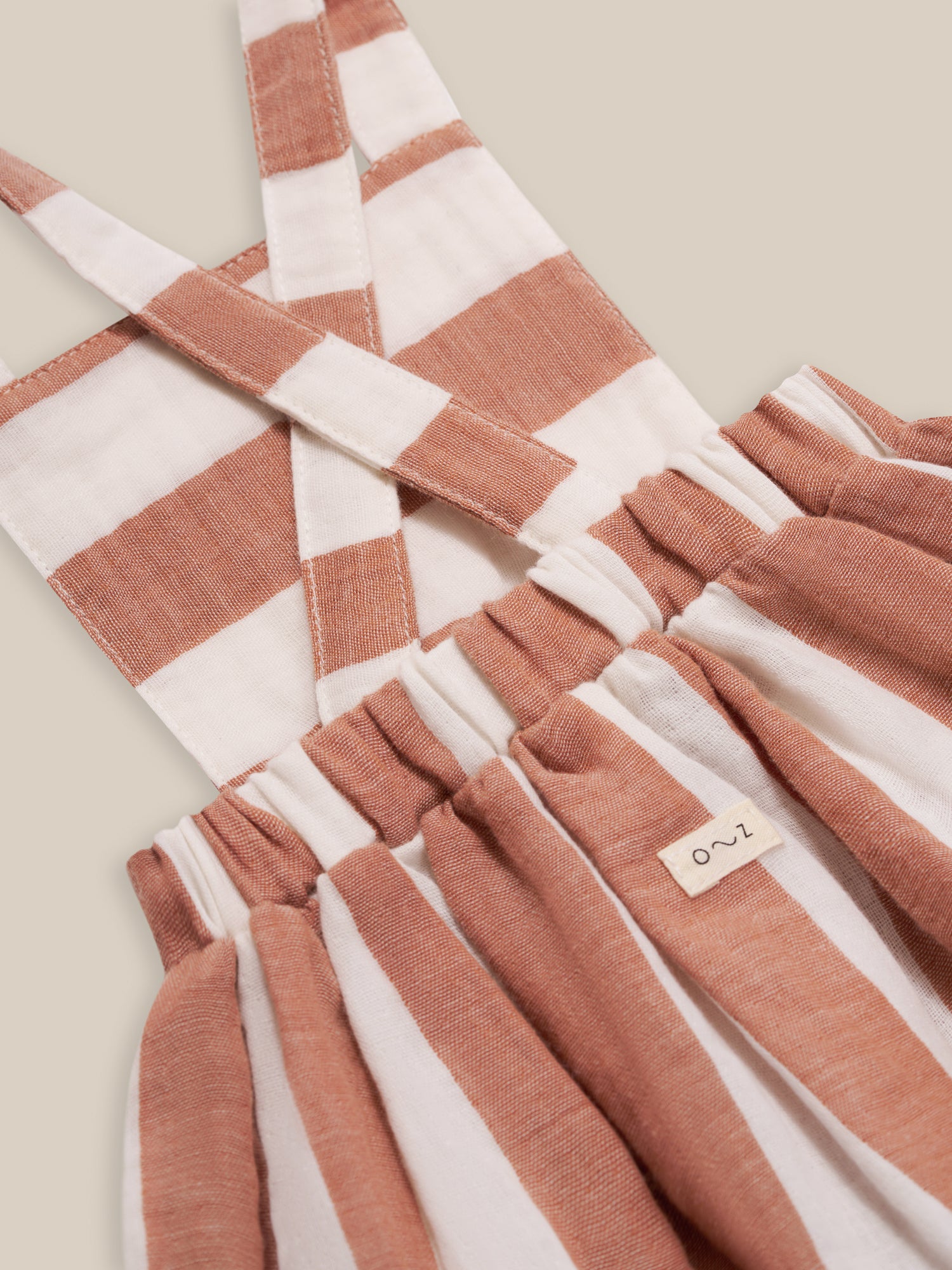 close up of toddler organic muslin red striped apron skirt with cross back & elastic waistband