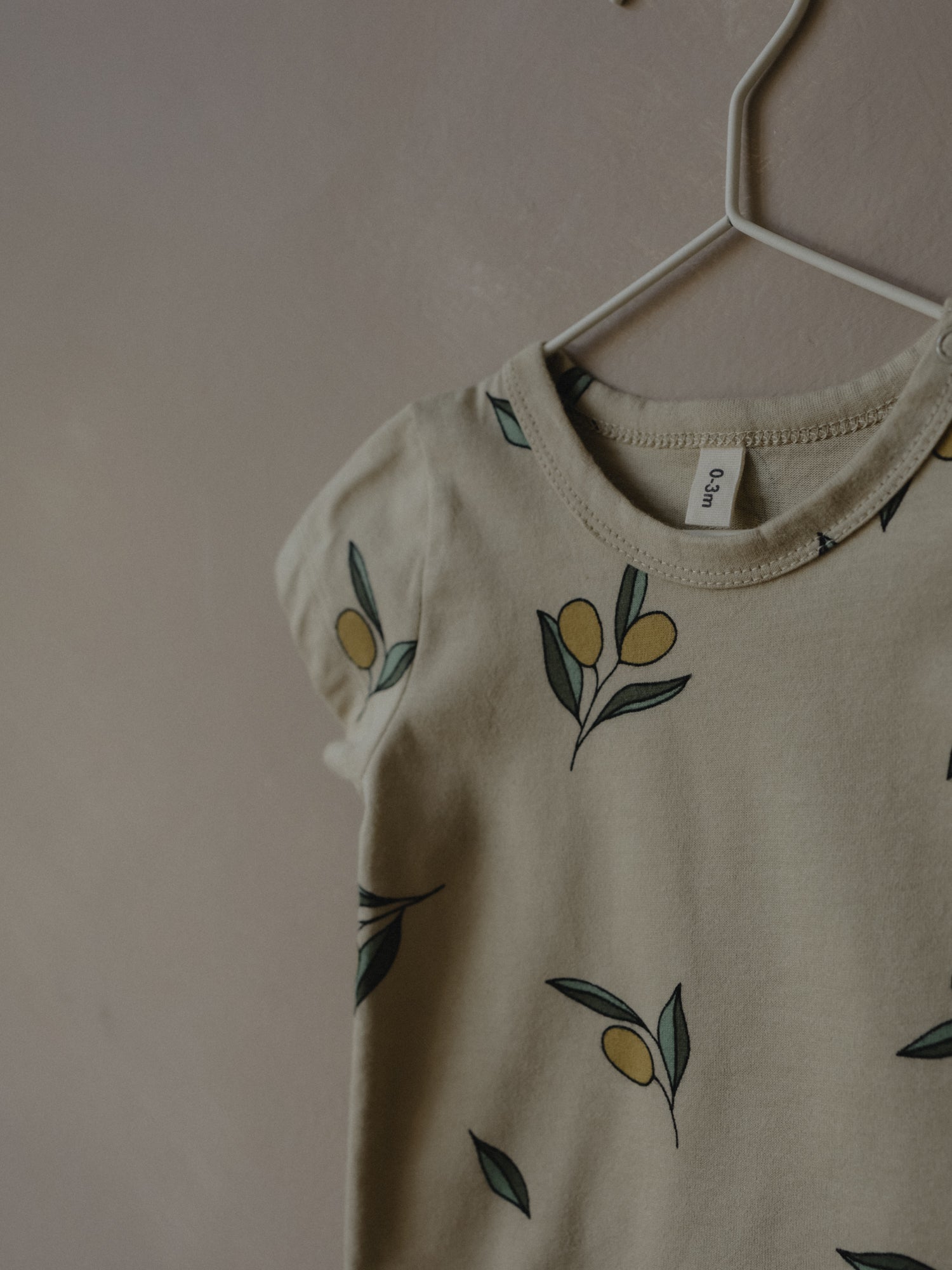 short sleeve baby bodysuit in cream with olives in details