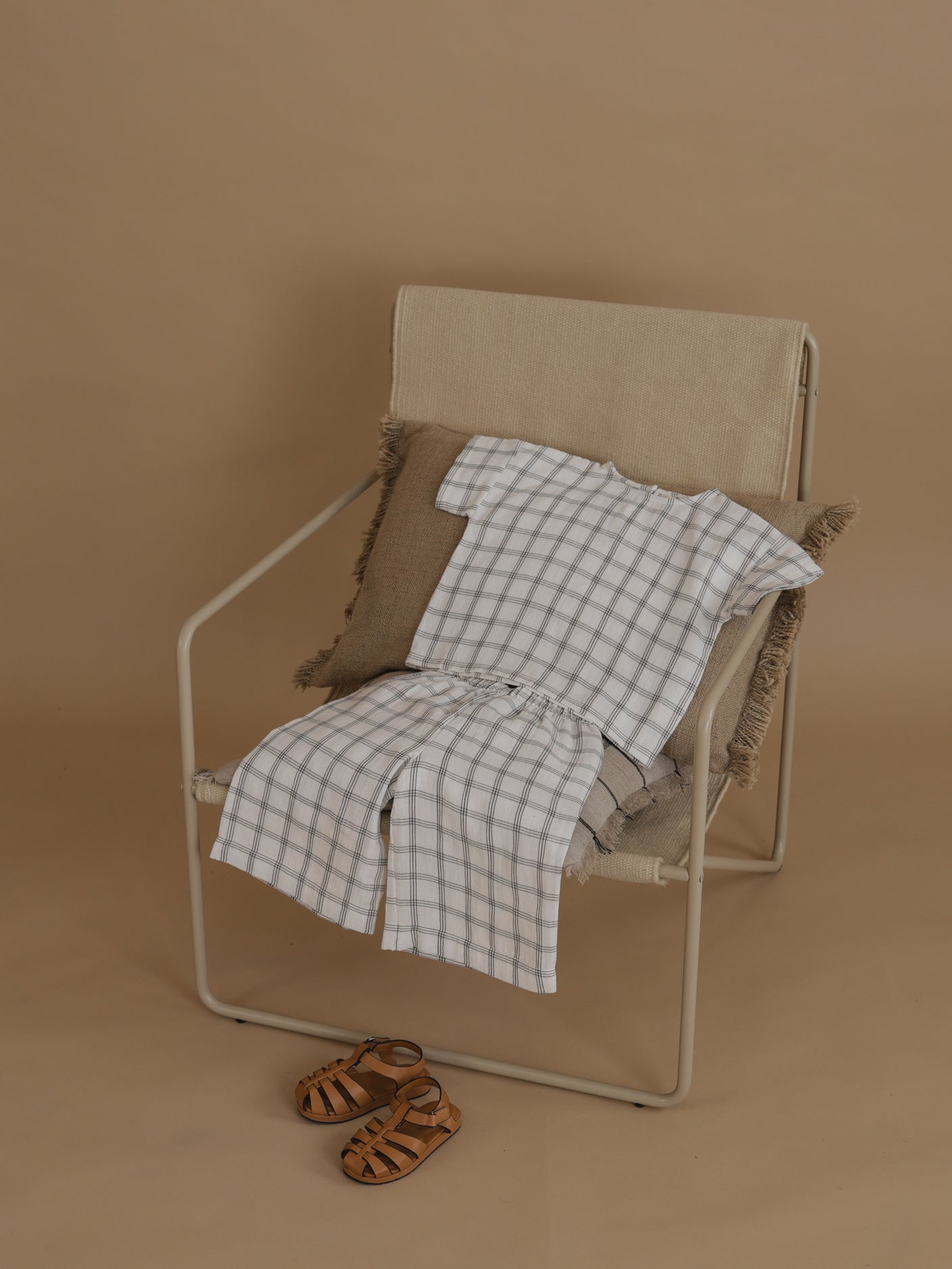 flat lay of matching boxy navy window check t-shirt & pants on chair, with sandals on floor