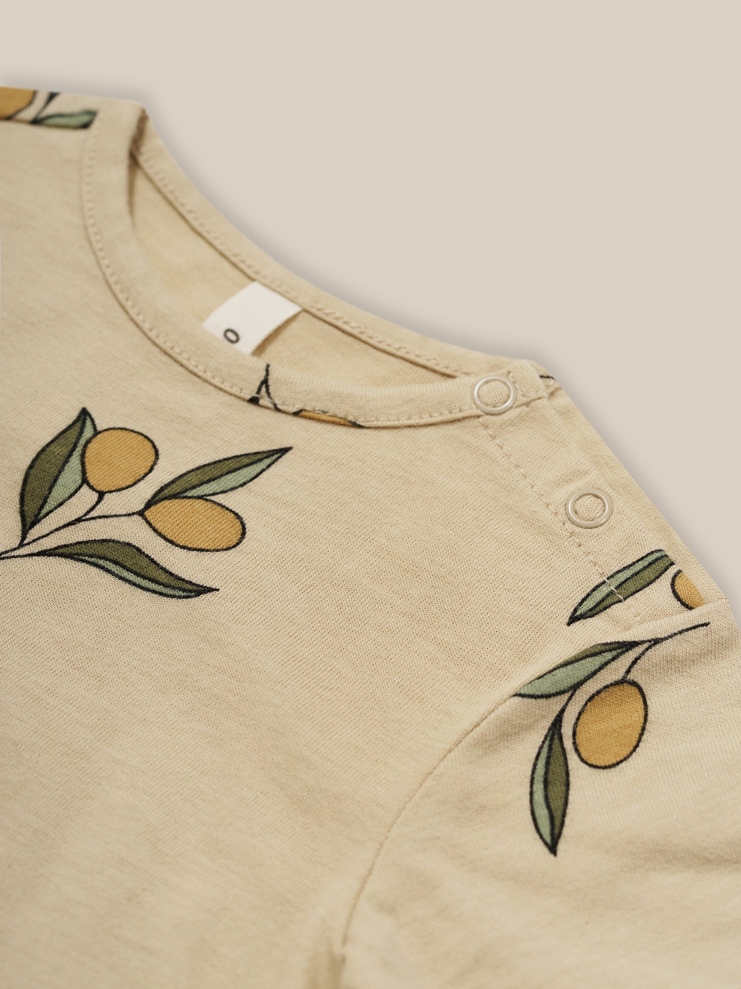 close up of baby organic cotton crew neck cream t-shirt with olive print & shoulder poppers