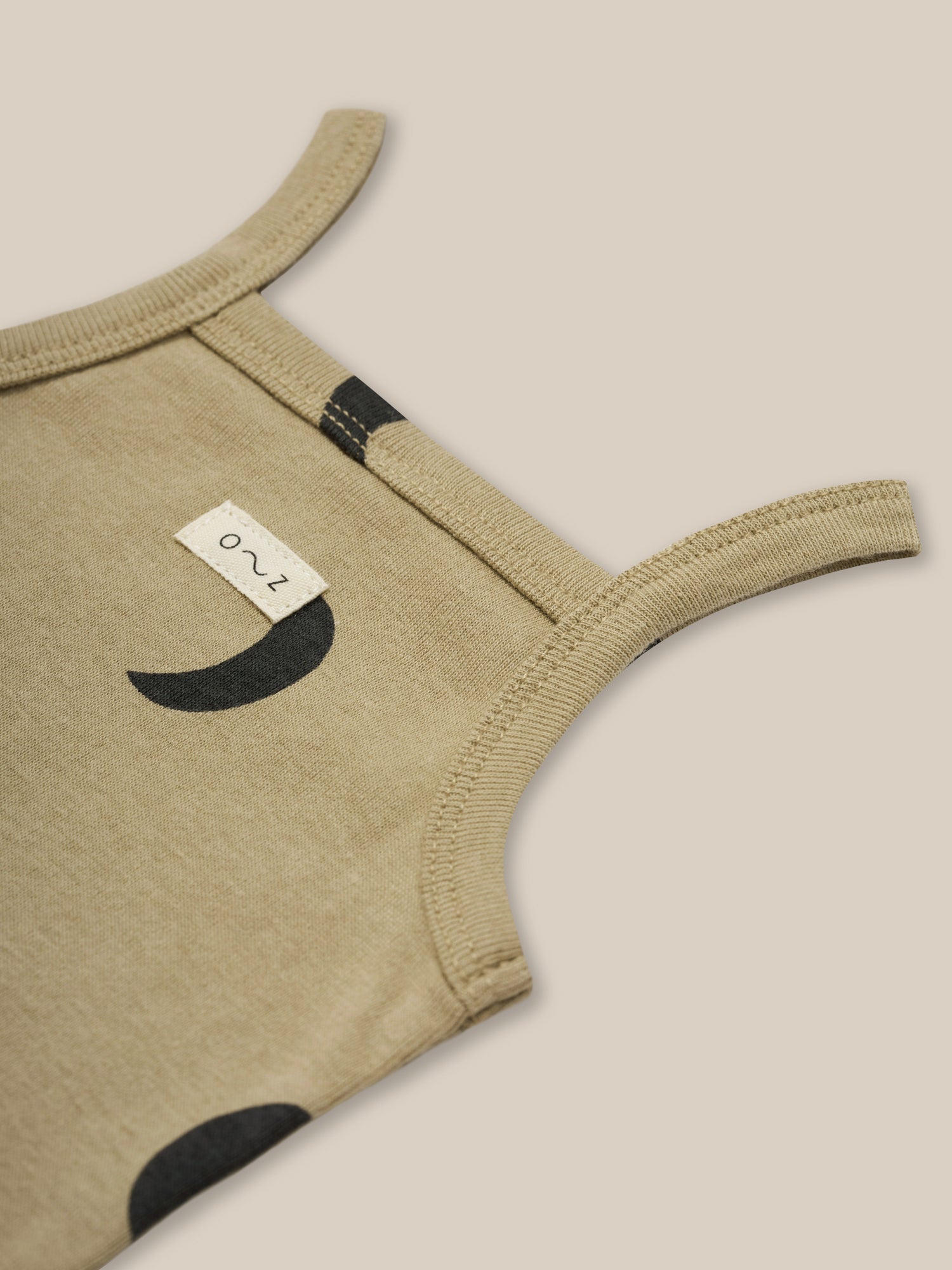 close up of baby dusky beige organic ribbed cotton tank bodysuit with black moon print