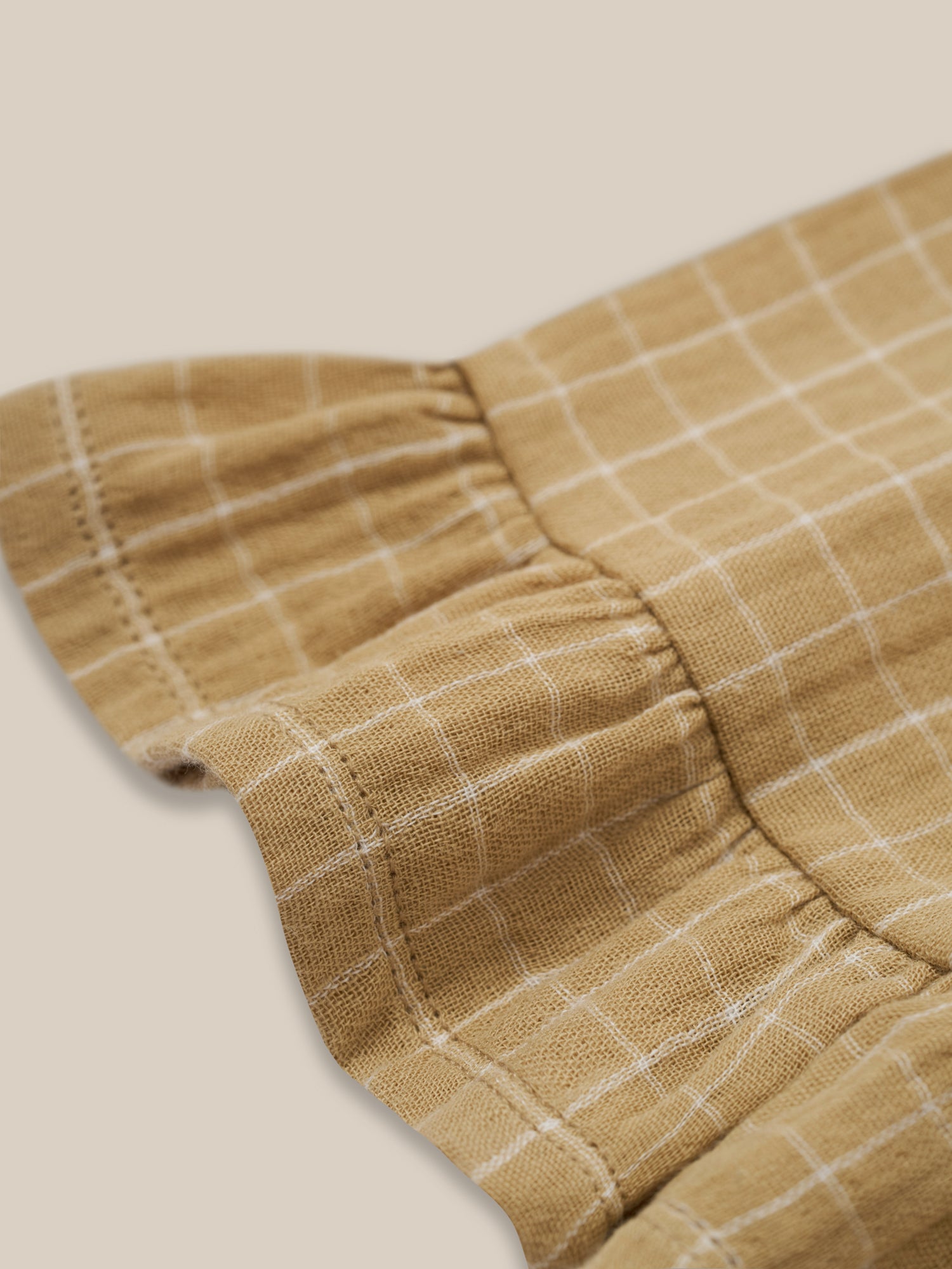 close up of toddler wheat gold grid check organic muslin culottes with frill hem