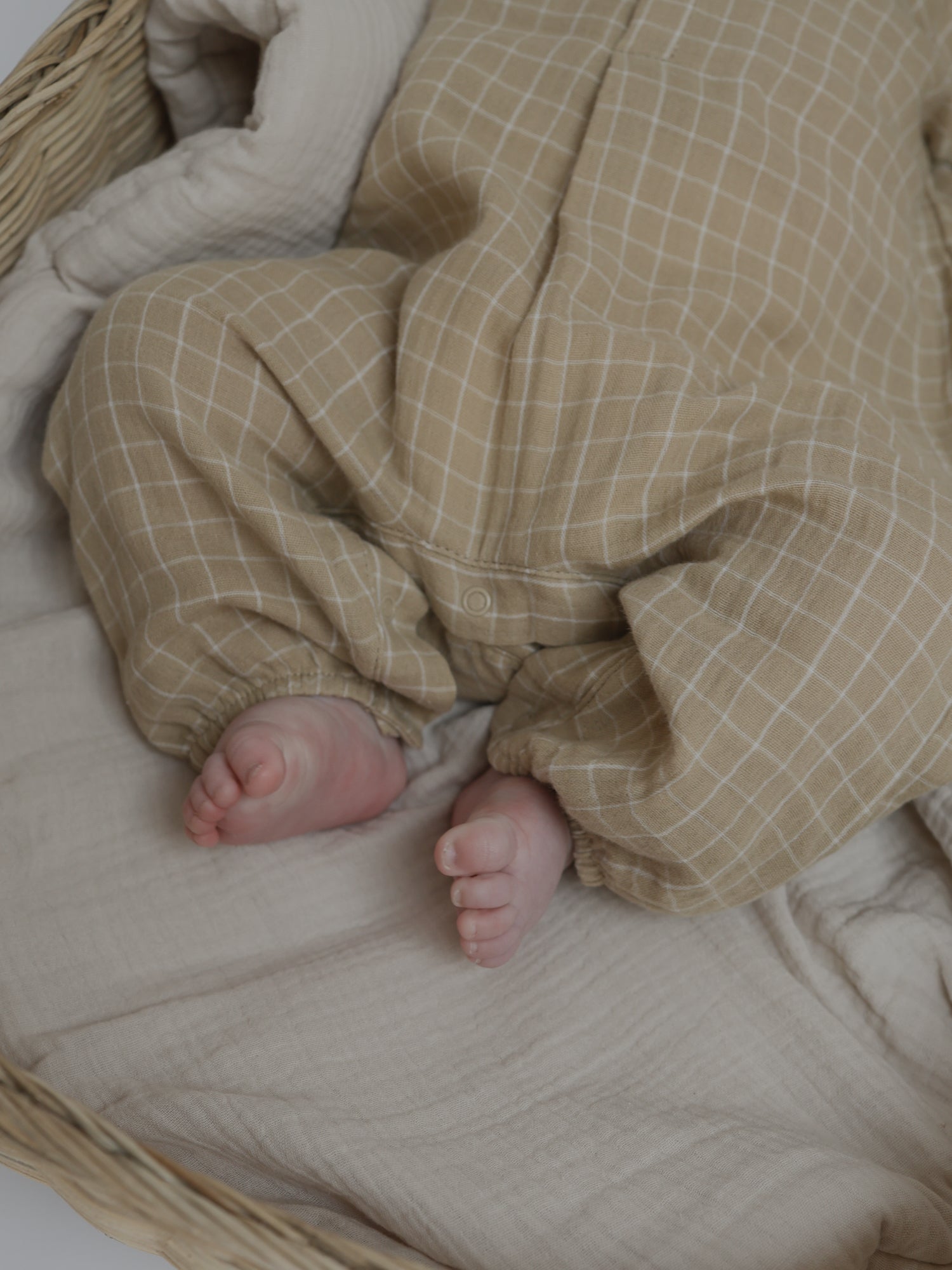 baby in soft breathable organic muslin onesie with timeless grid pattern & elastic cuffs