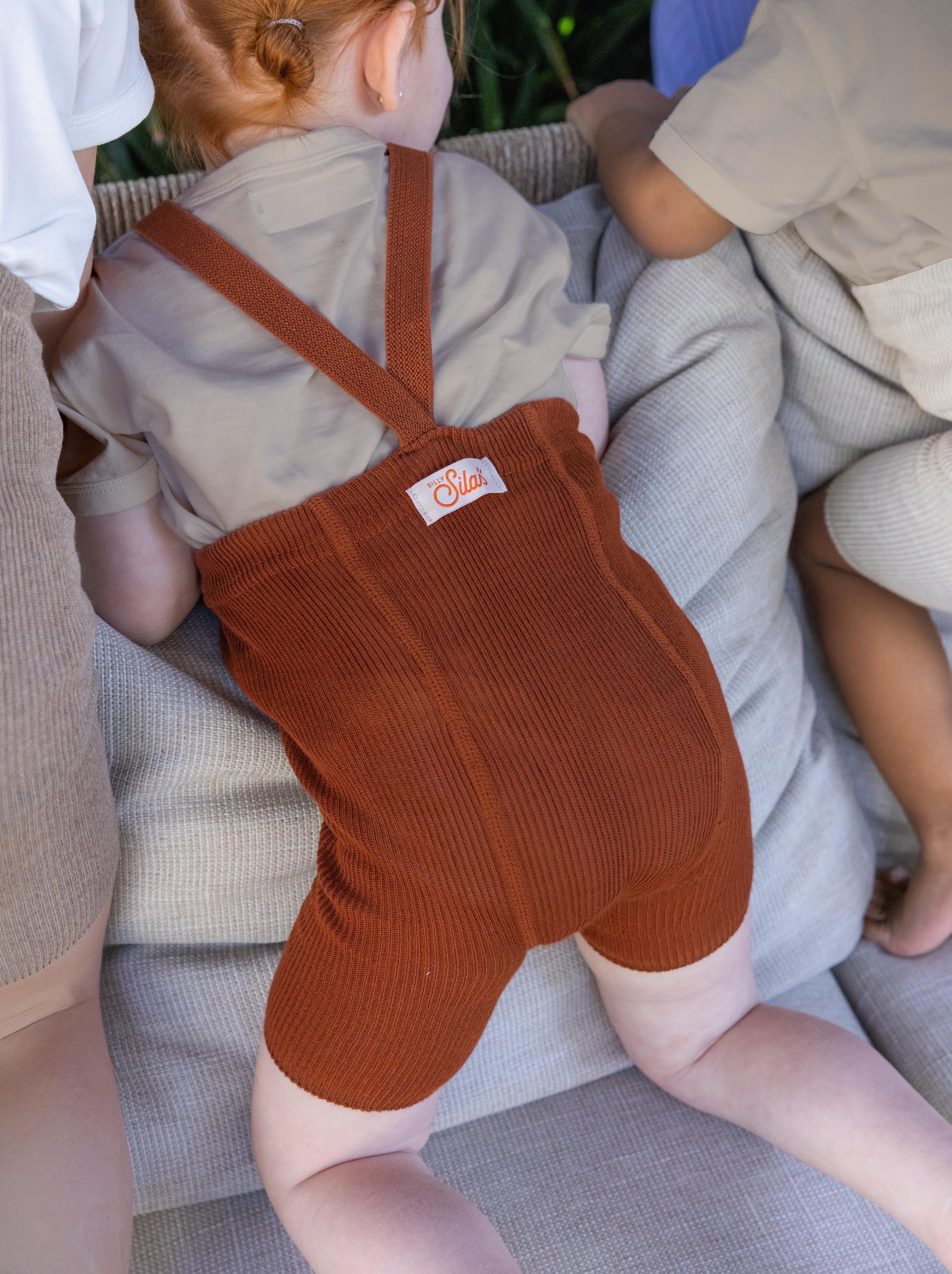 toddlers in cinnamon ribbed cotton shorty tights with braces playing on sofa