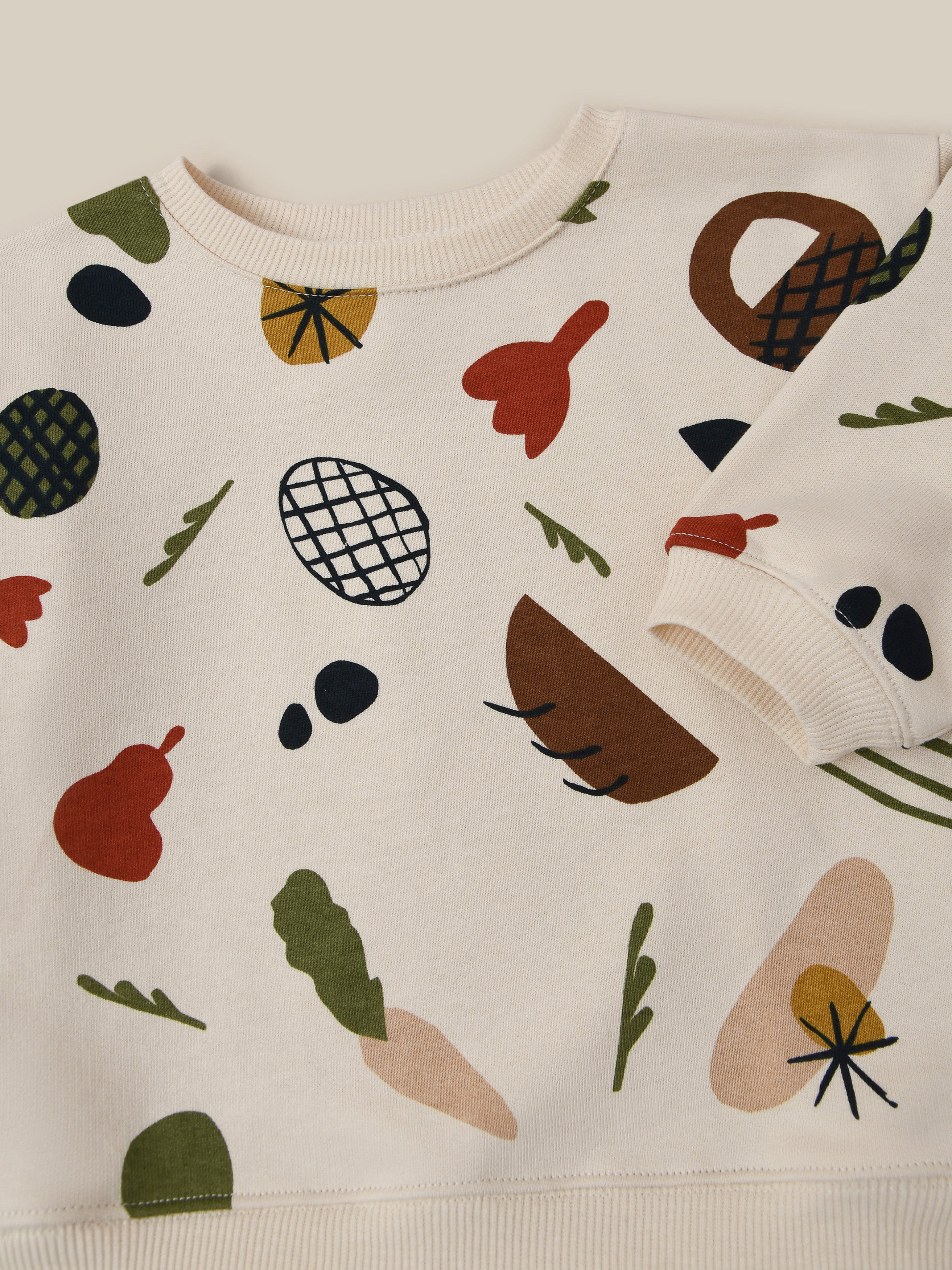 close up of undyed cotton cream sweatshirt with fruits vegetables & basket prints