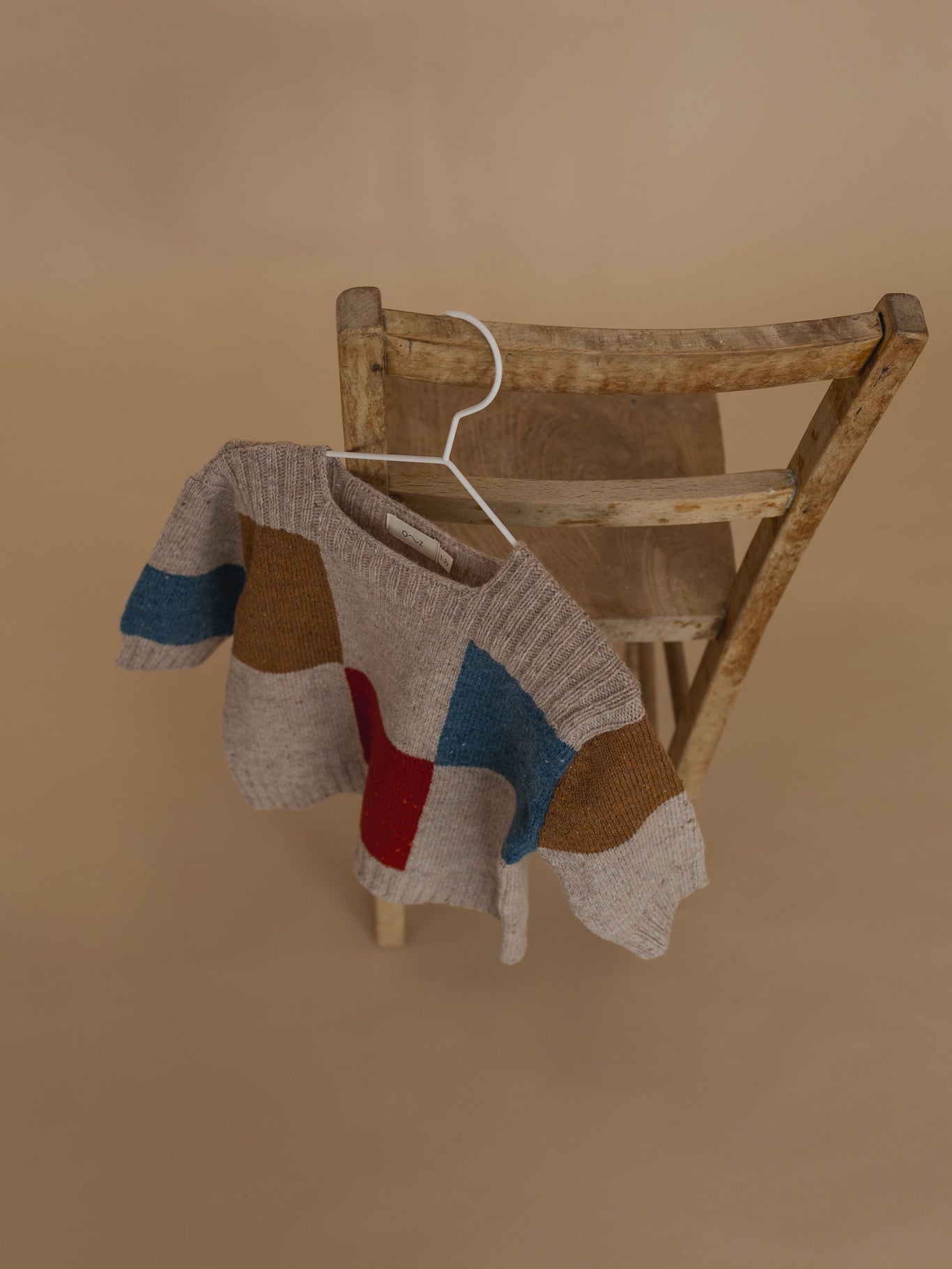 baby and toddler wool jumper with square neck, ribbed trim, colour-block patchwork hanging on chair