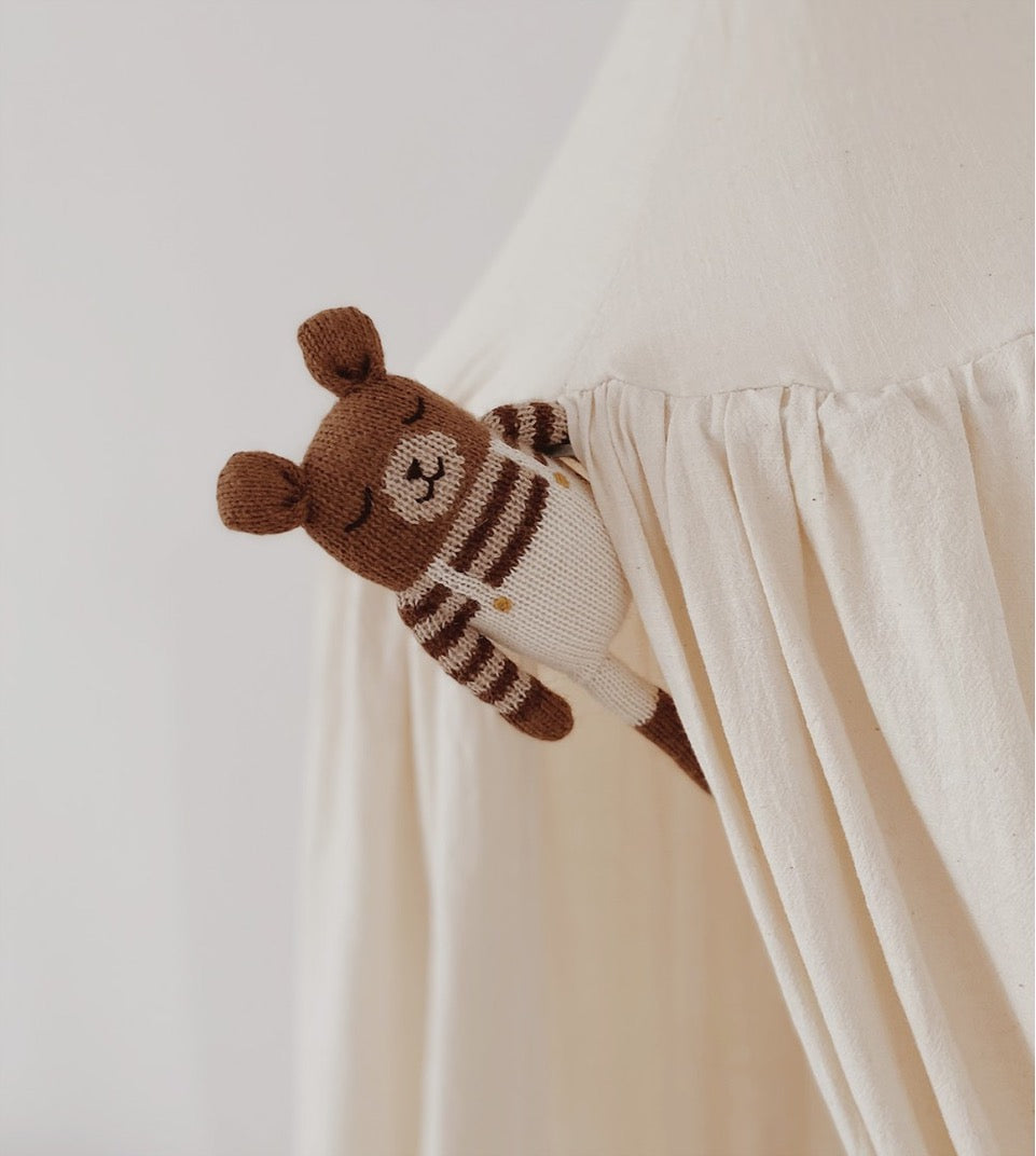 brown knitted wool teddy soft cuddly toy in stripes sweater & ecru overalls popping out of canopy