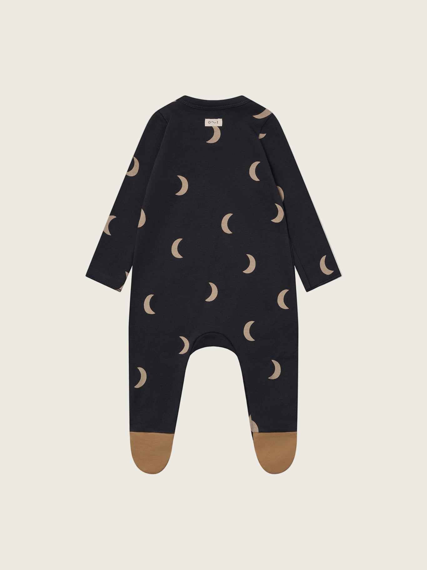Black baby onesie with moon pattern on a beige background