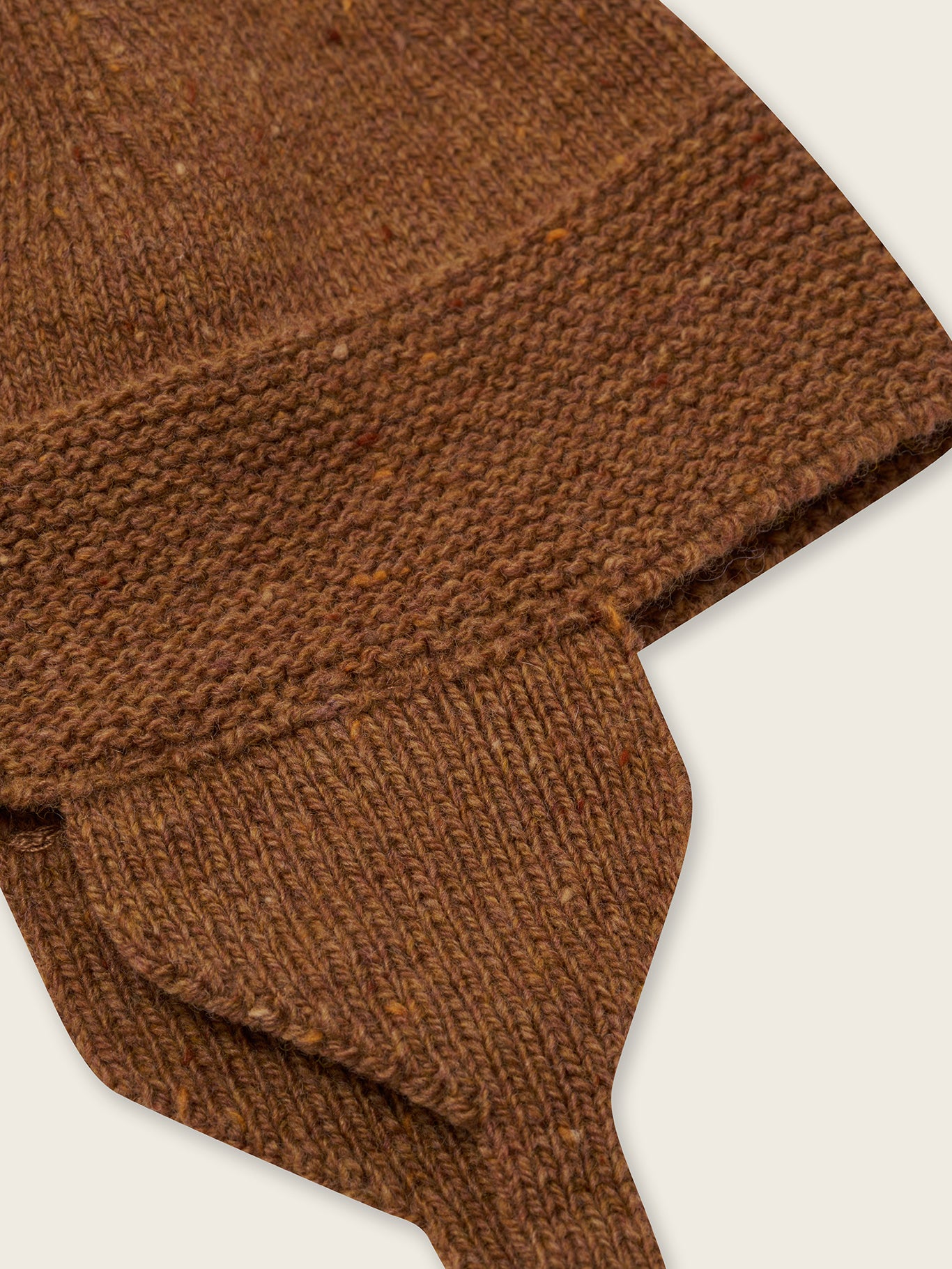 close up of wool hat in chestnut brown with red tassel and chin tie