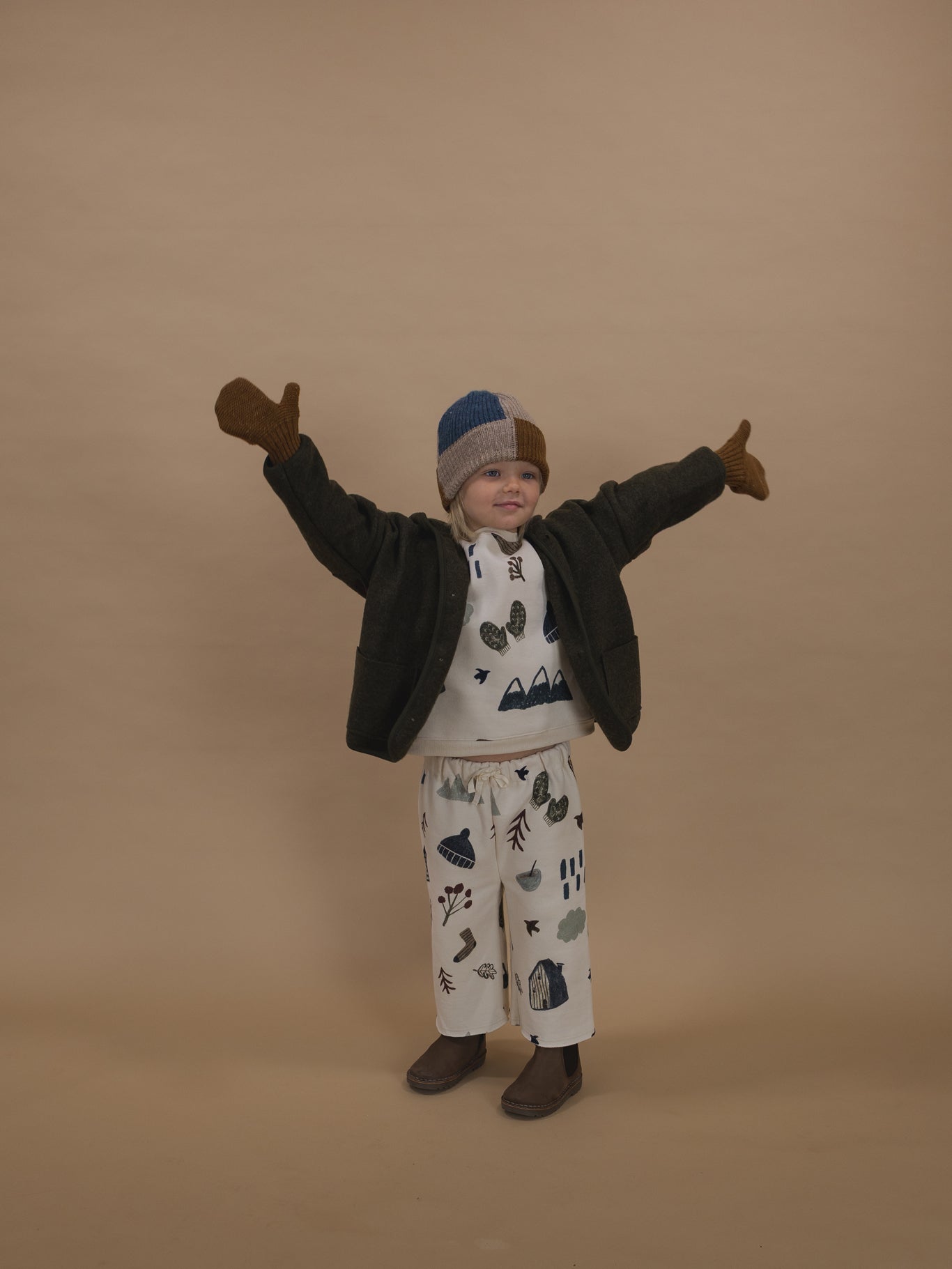 toddler in matching sweatshirt & pants, wool jacket with chestnut brown wool mittens, with open arms