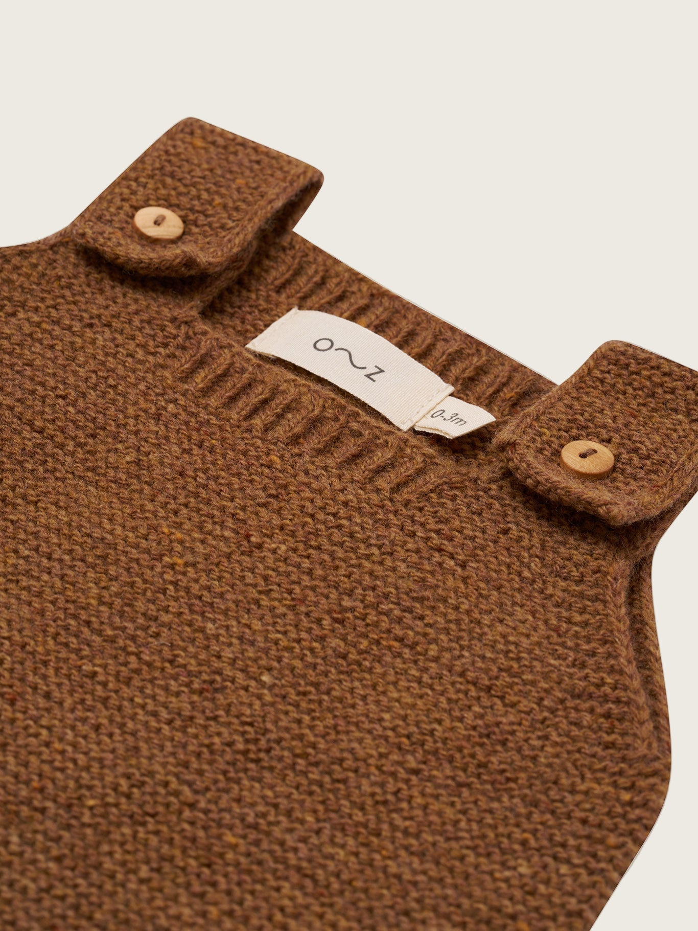 close up of wool salopette in chestnut brown with button straps and ribbed cuffs