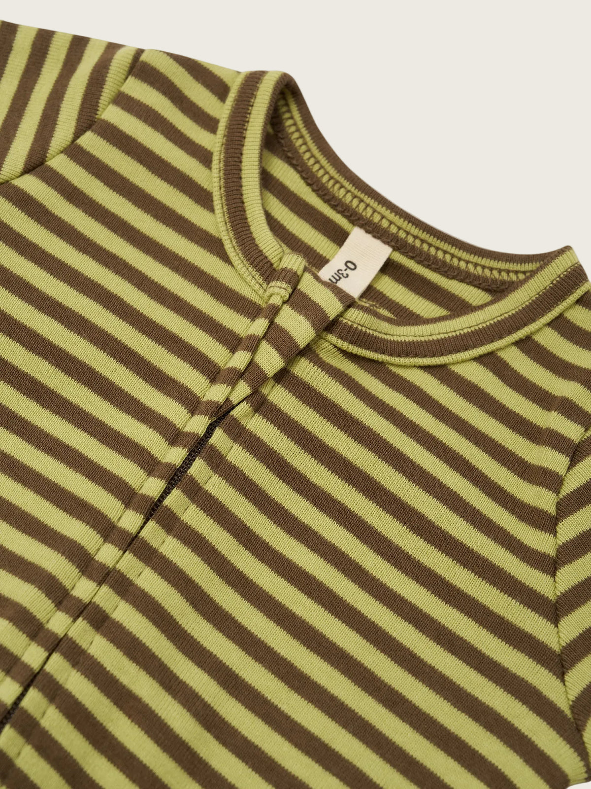 Close-up of a striped knit garment, likely a baby top or romper, with alternating olive green and dark brown horizontal stripes. A small fabric tag is visible at the inside neckline.