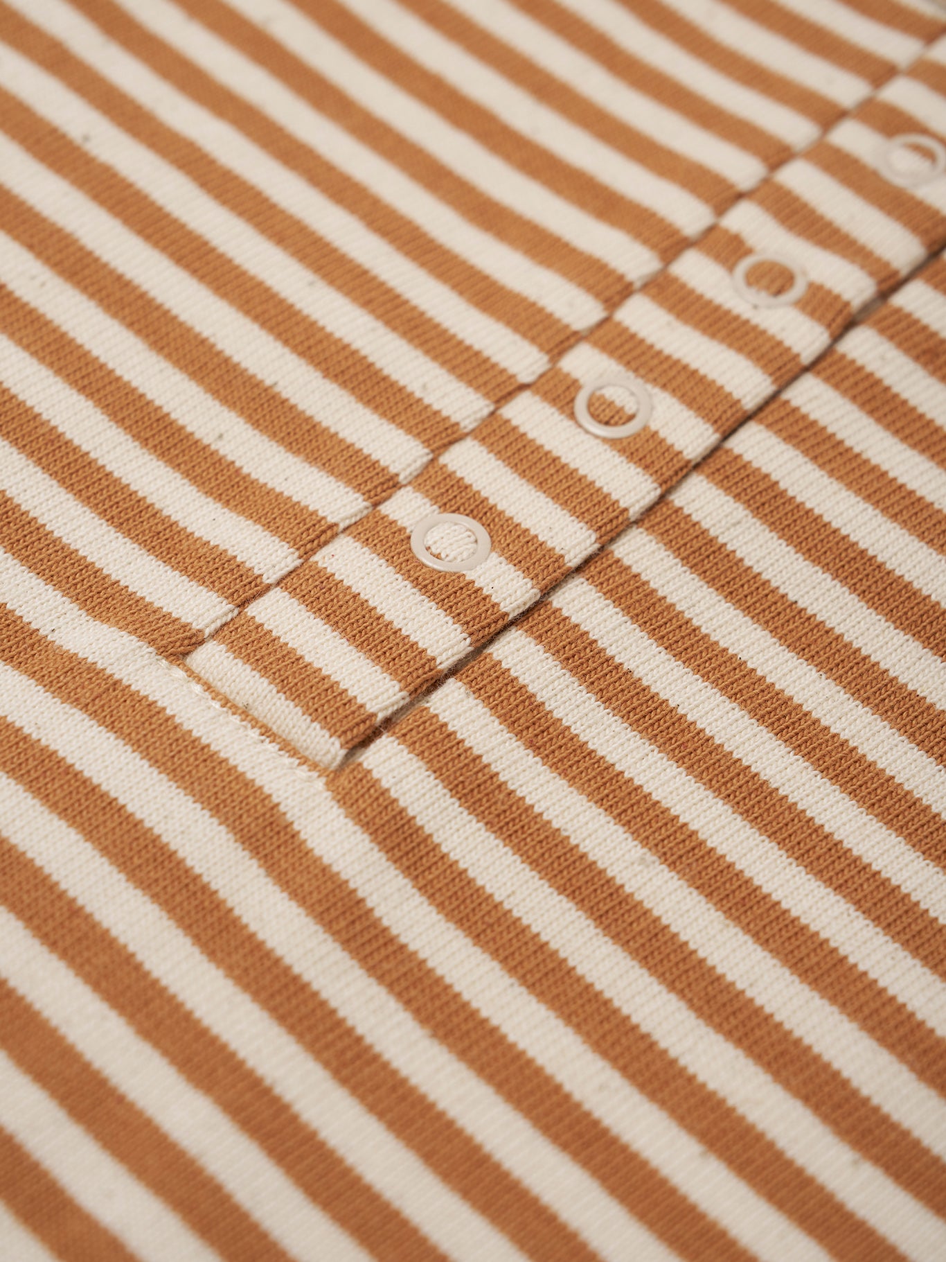 Close-up of brown and white striped fabric with button details