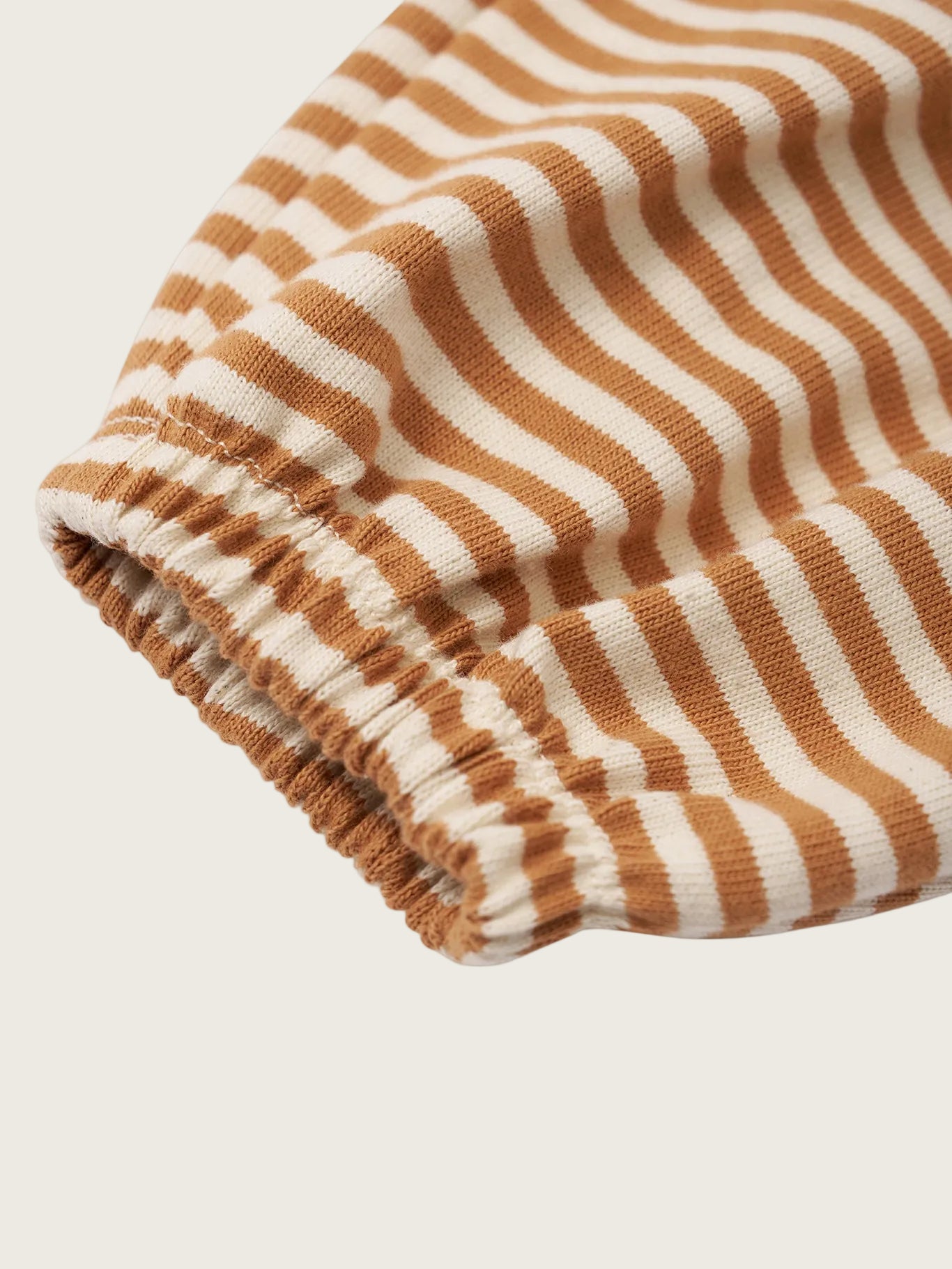 Folded fabric with copper and white vertical stripes on a white background