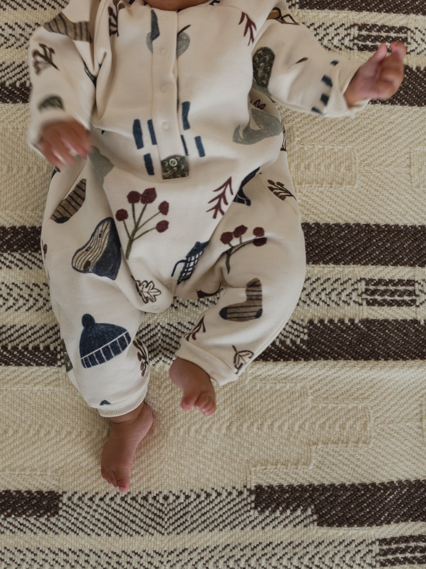 close up of a baby in cream undyed cotton onesie with cosy nature-themed hand-drawn prints