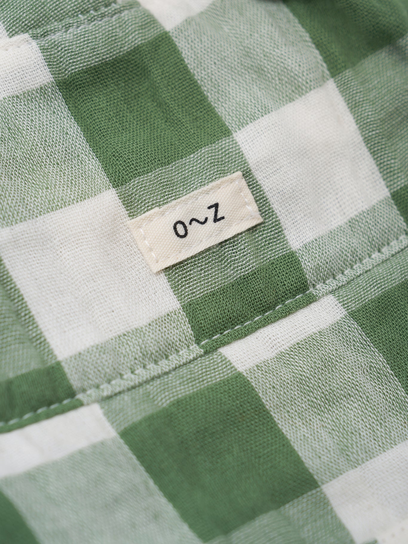 Close-up of a green and white checkered fabric with a label on a green background