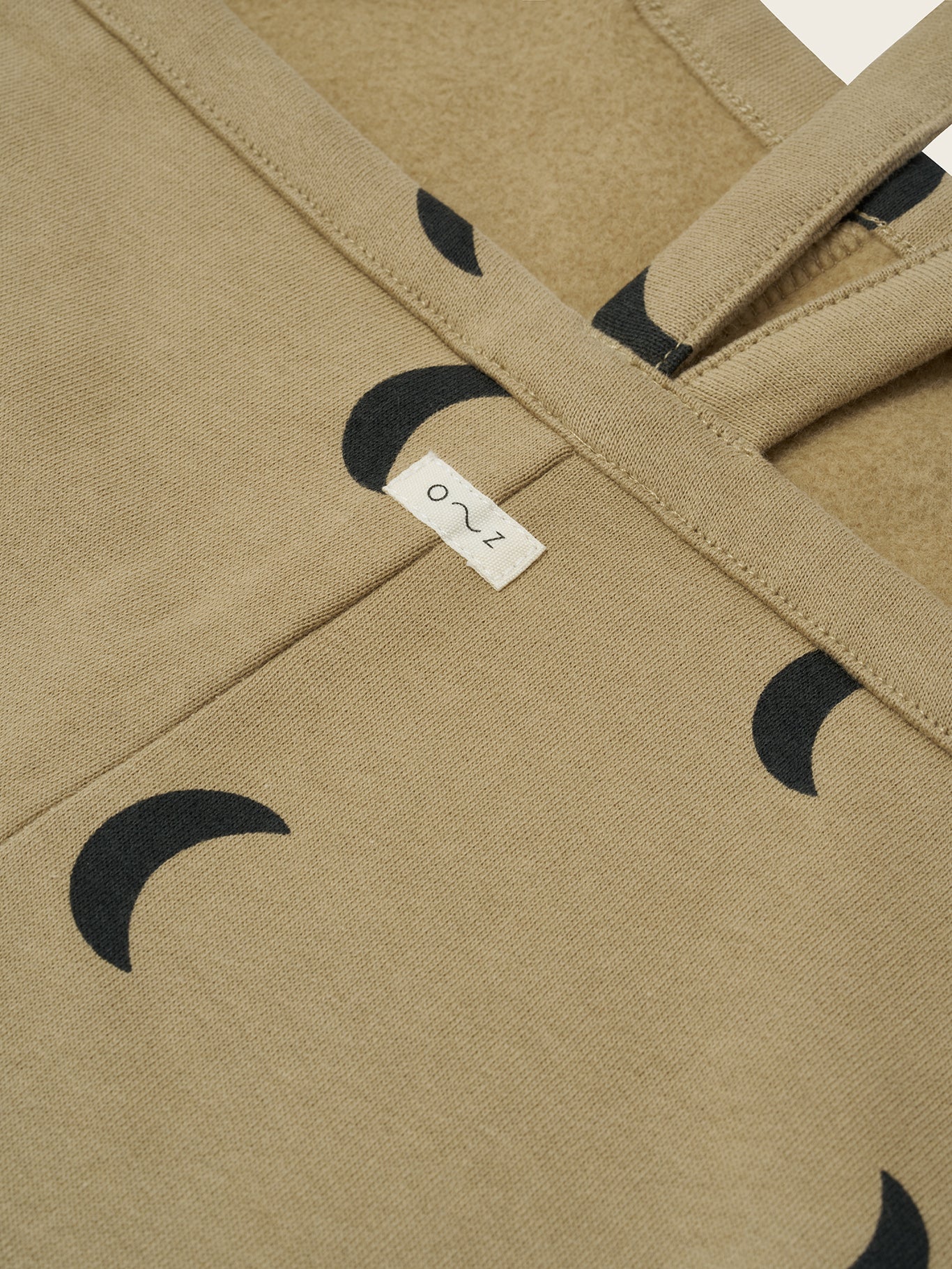 close up of toddler dusky beige oversized boxy terry cotton dungarees with black crescent moon print