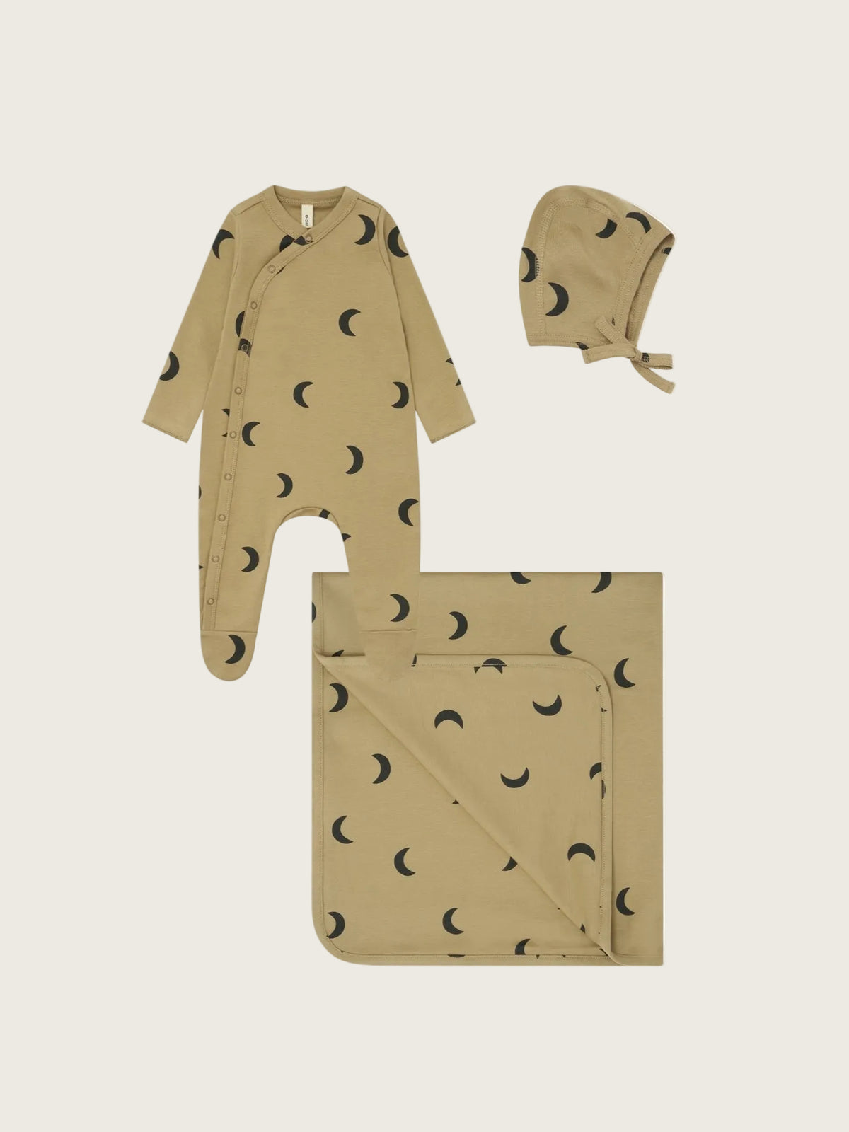 A three-piece baby clothing set in a warm tan/khaki color with a black crescent moon pattern, including a footed sleeper, a bonnet, and a blanket, displayed on a solid white background.