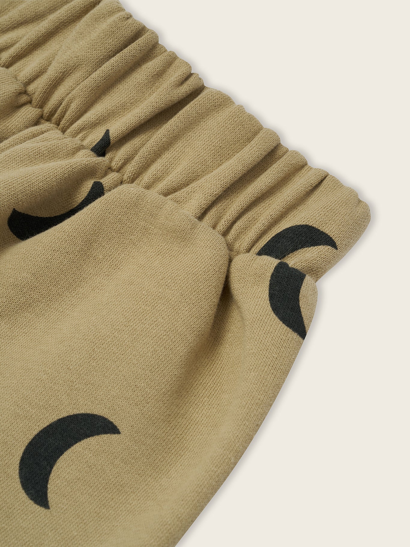 close up of dusky beige trousers with black crescent moon print and elastic waistband