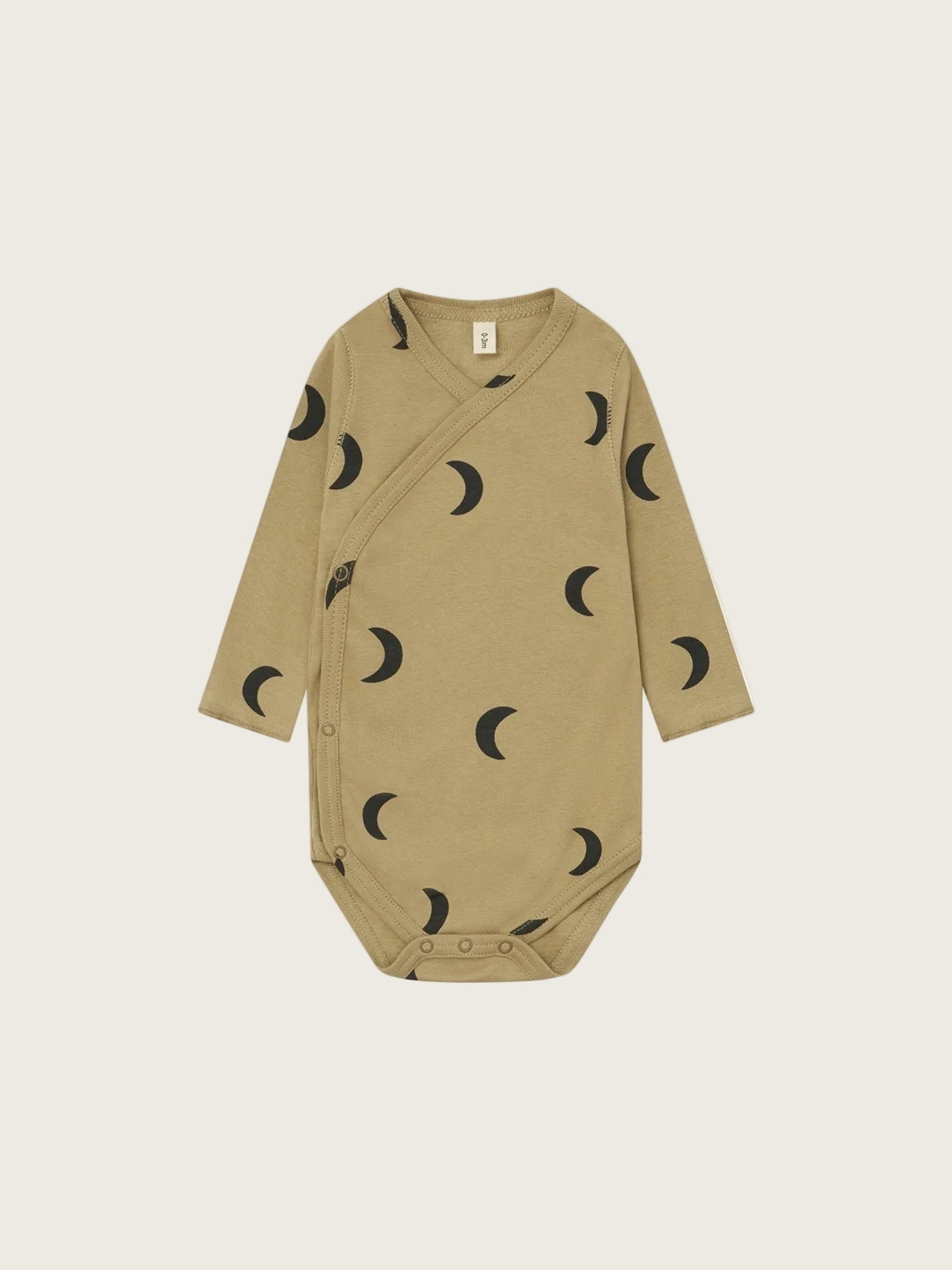 A long-sleeve baby bodysuit in a warm tan/khaki color, featuring an all-over black crescent moon pattern, displayed flat against a solid white background.