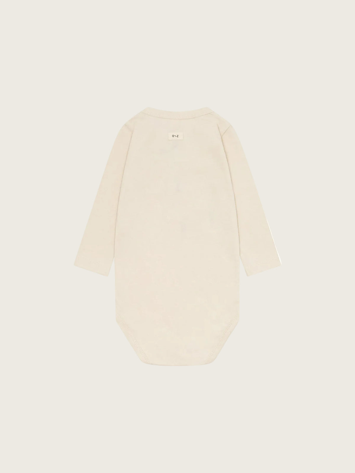 A long-sleeve baby bodysuit in a light cream or off-white color, shown from the back against a solid, very light beige background.