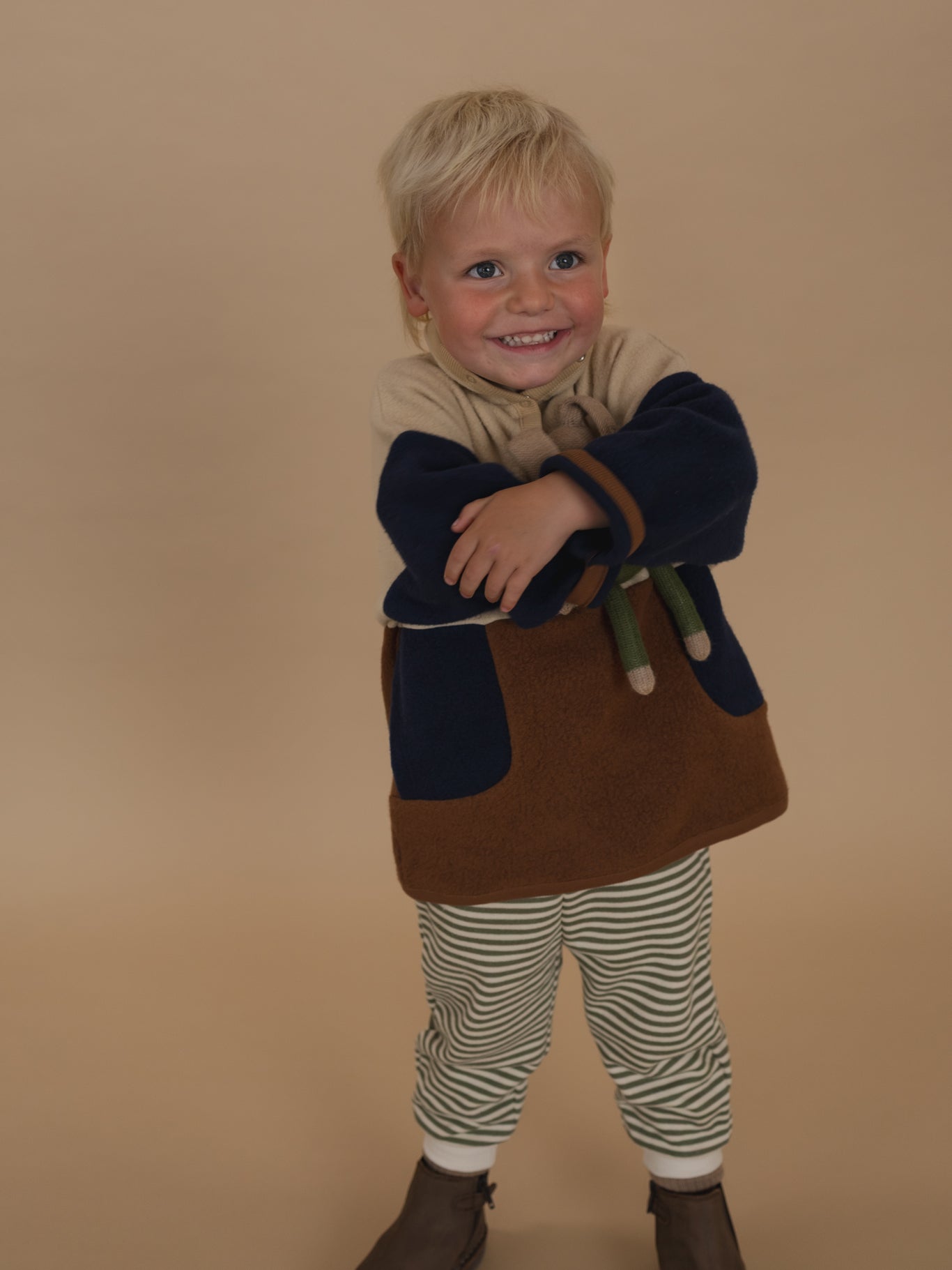 toddler in fern green and white striped sweatpants and colour block sweater, hugging a plushie