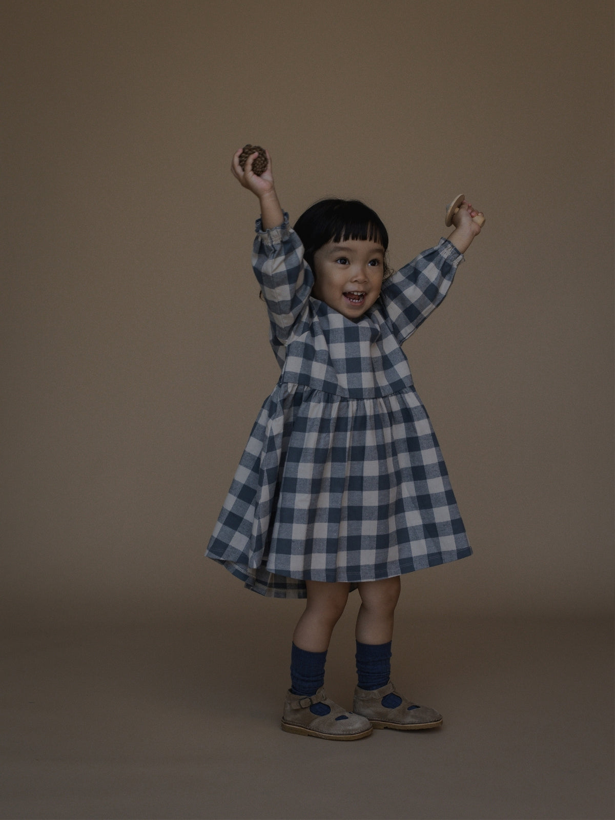 A young child wearing a blue and white gingham dress