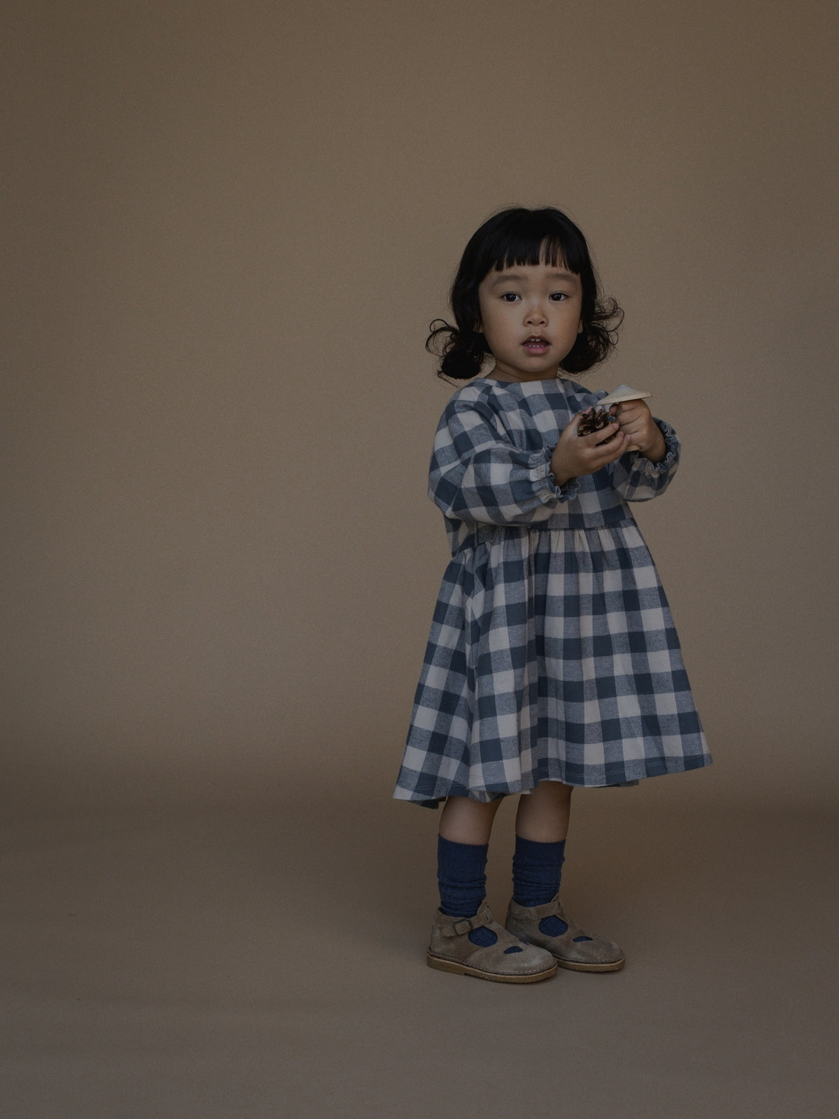 A child wearing a blue and white gingham dress