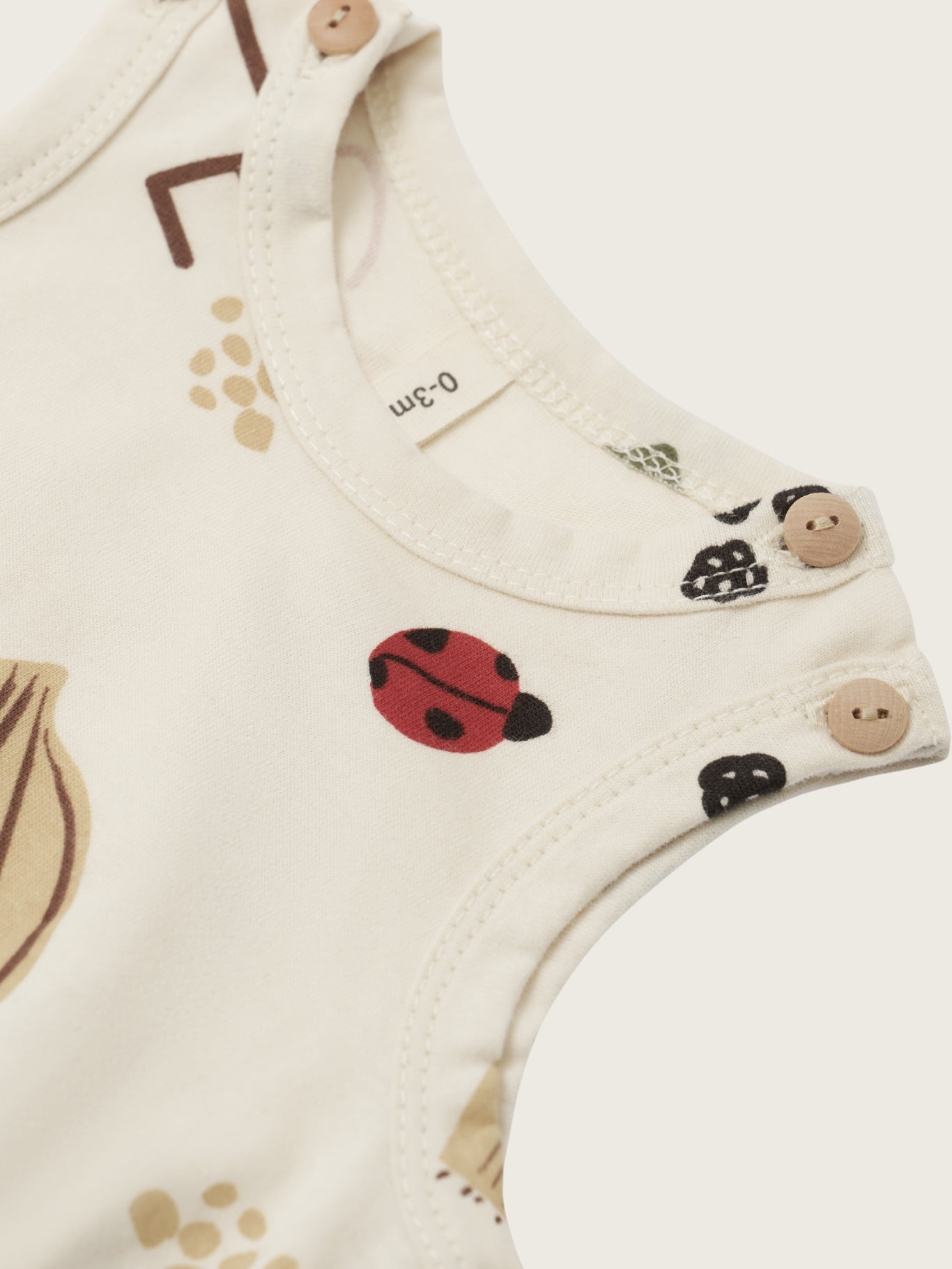 Baby bodysuit with ladybug and leaf patterns on a white background