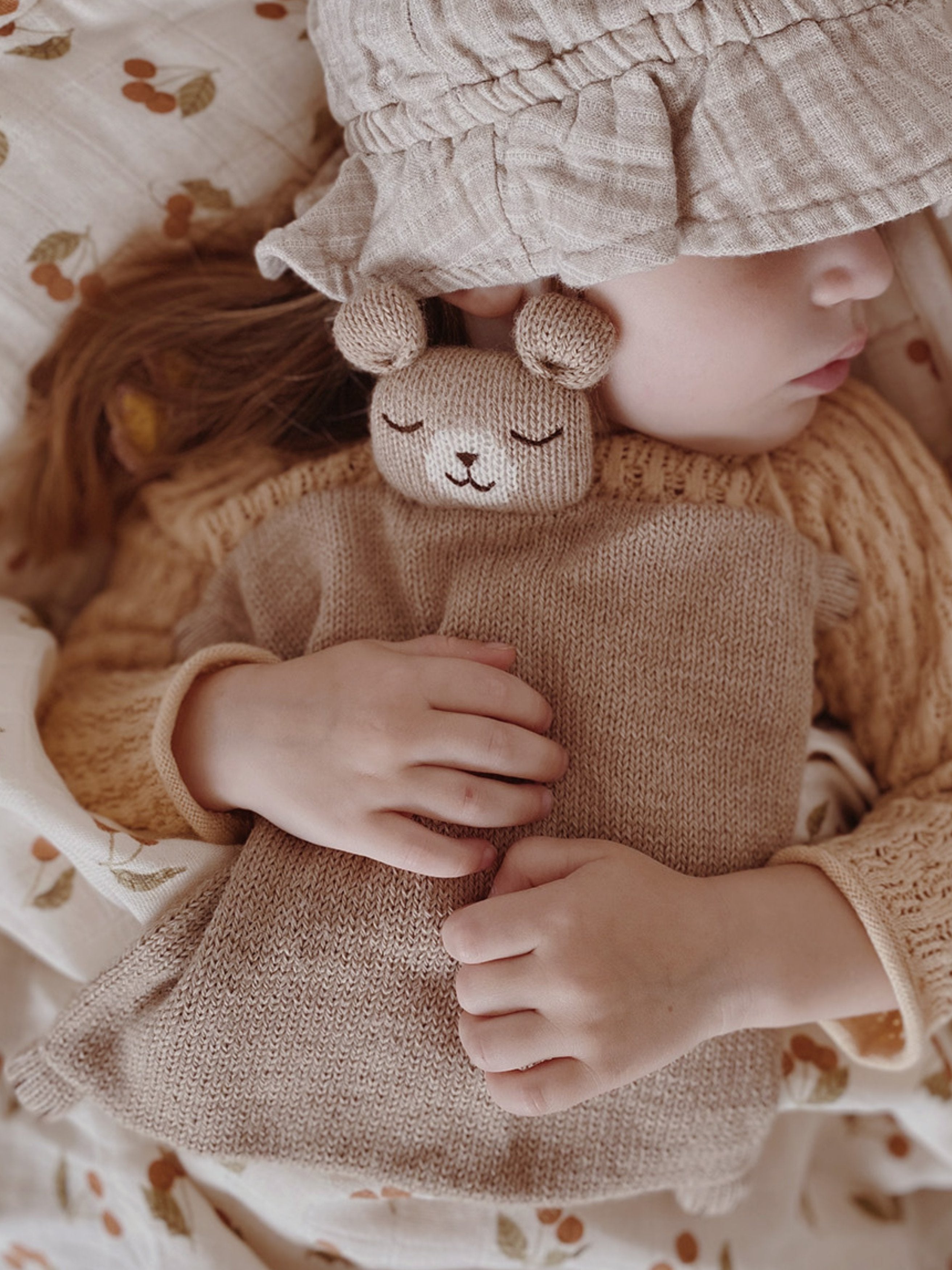 toddler hugging knitted wool teddy cuddle cloth in sand with soft square body and bear head detail