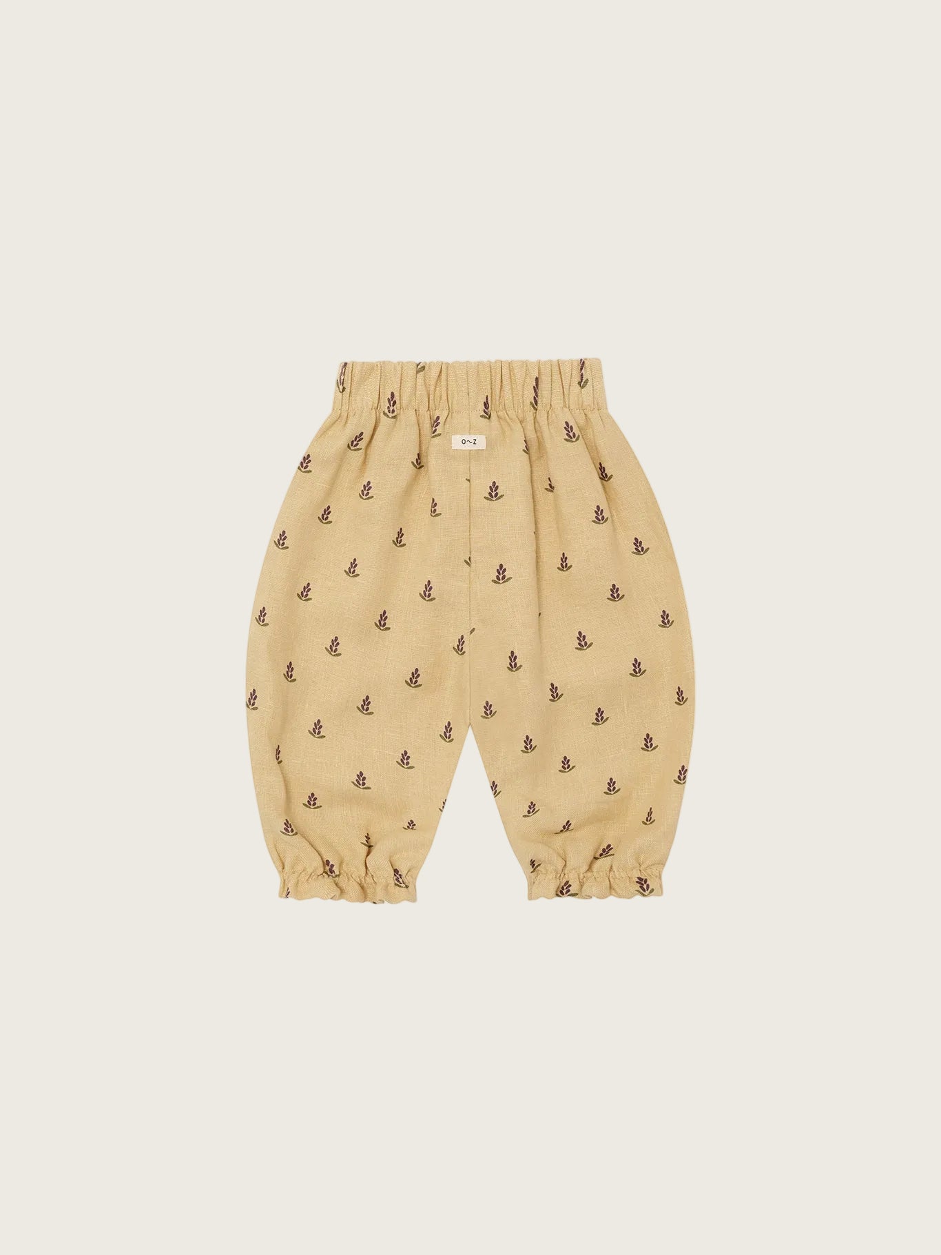 Beige baby pants with small patterns on a white background