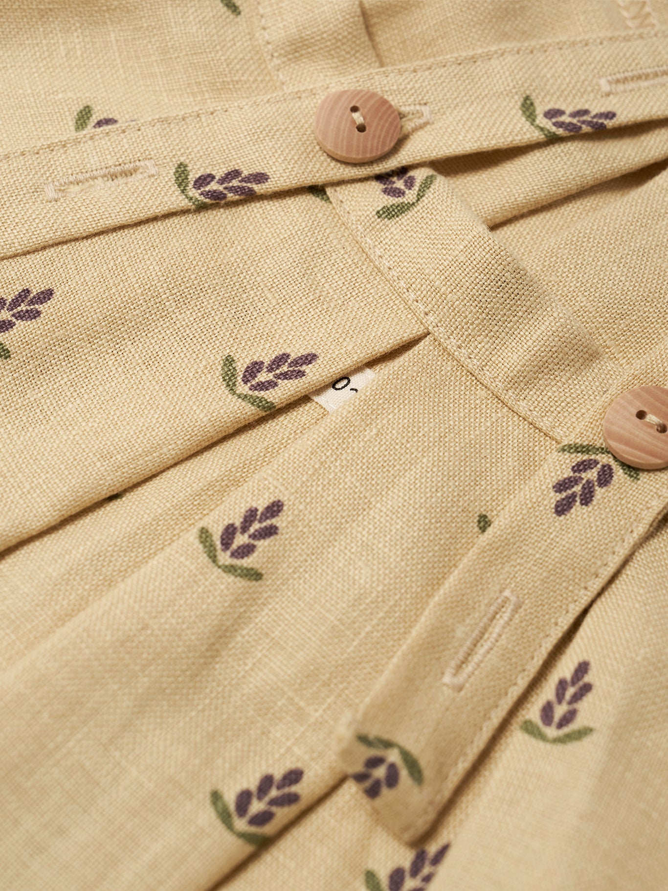 Close-up of beige fabric with floral patterns and wooden buttons.