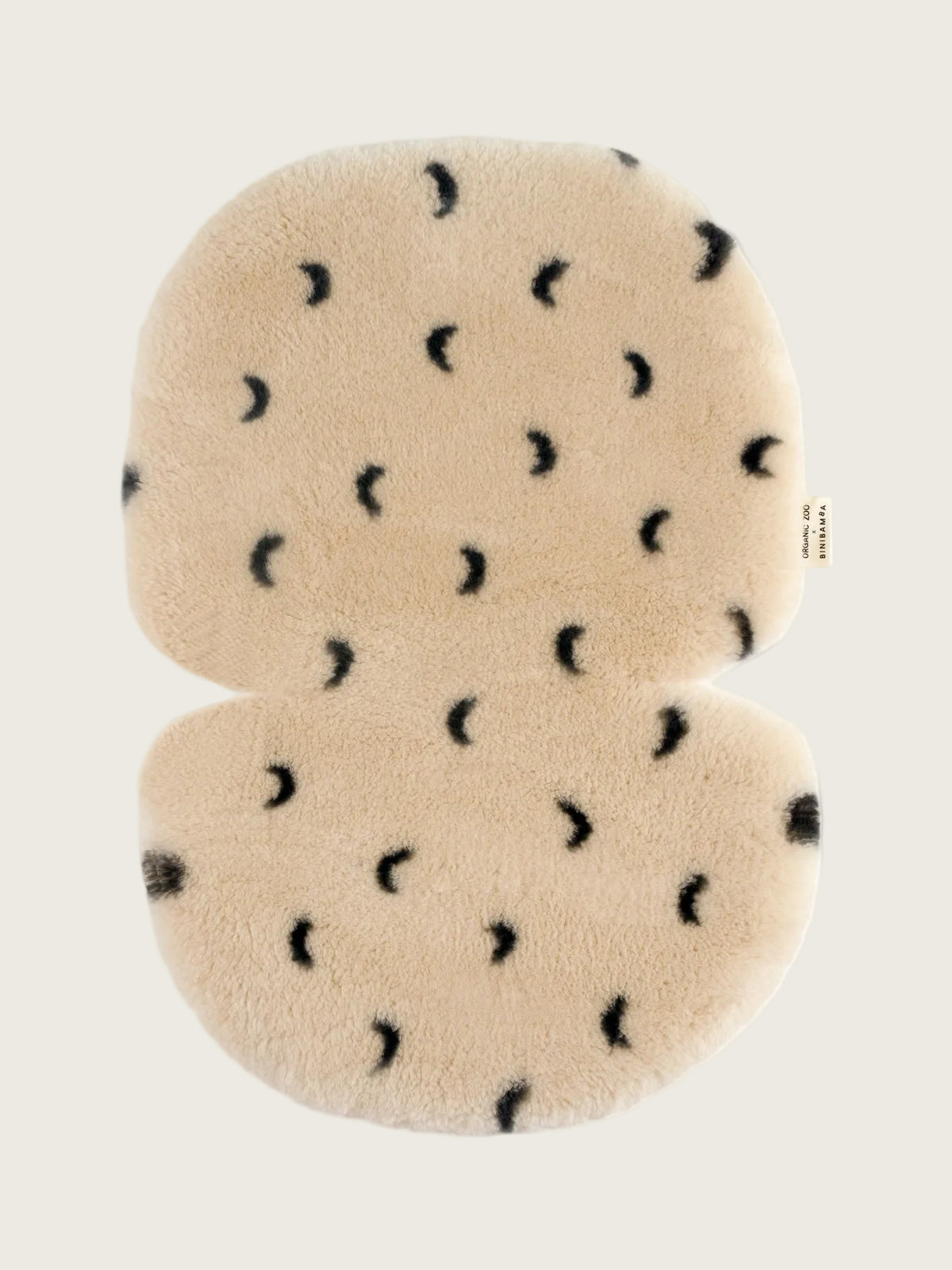 A plush, buggy liner set in cream-colored faux fur with a black crescent moon pattern, shown against a plain white background.