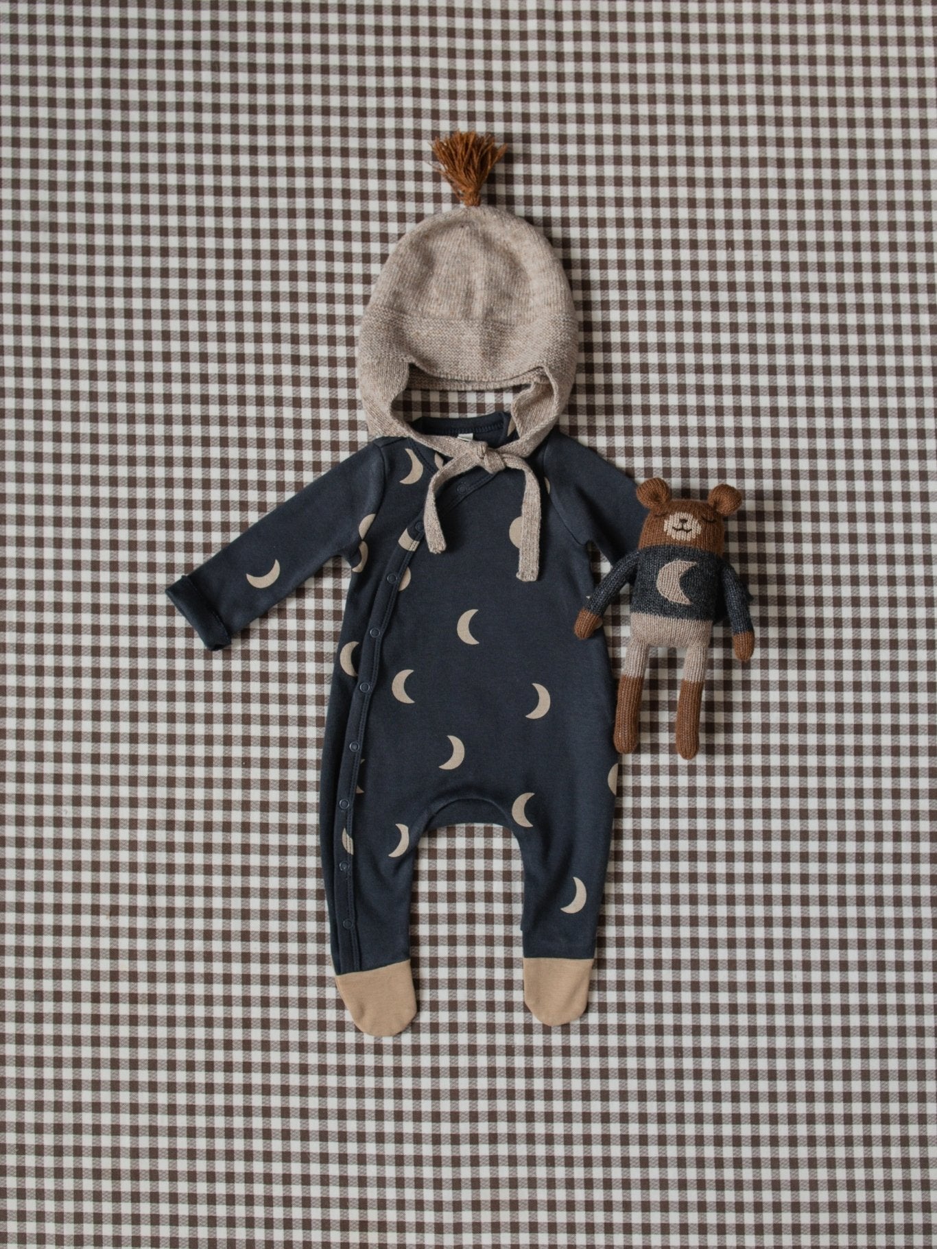 Baby outfit with hat and toy on a checkered background