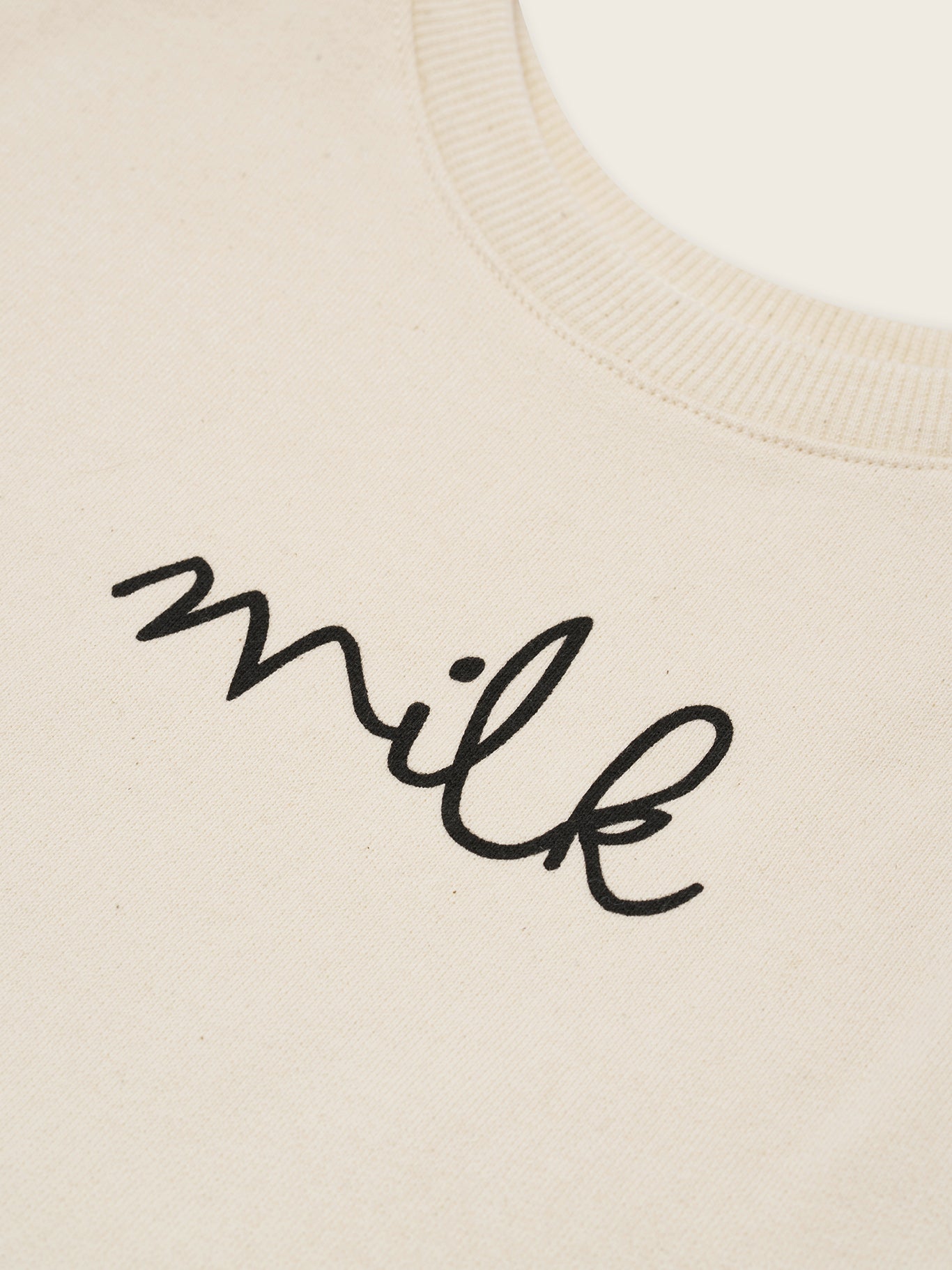 close up of cream undyed cotton boxy drop shoulder sweatshirt with milk text