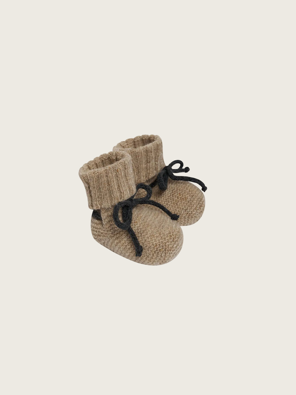 A pair of beige knit baby booties with black laces, shown on a plain white background.