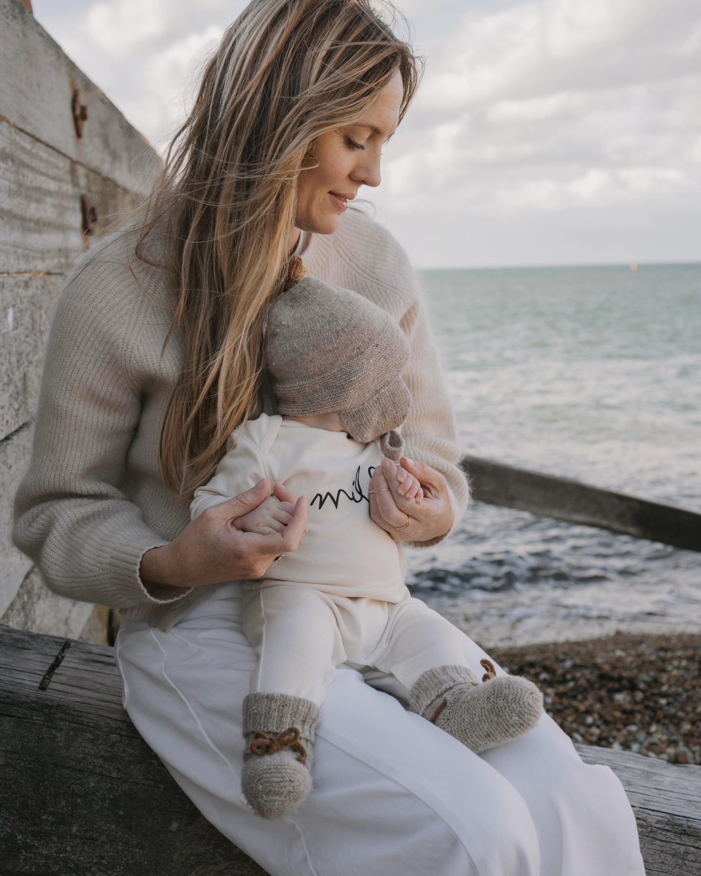 Mom holding a baby in a undyed cotton milk playsuit