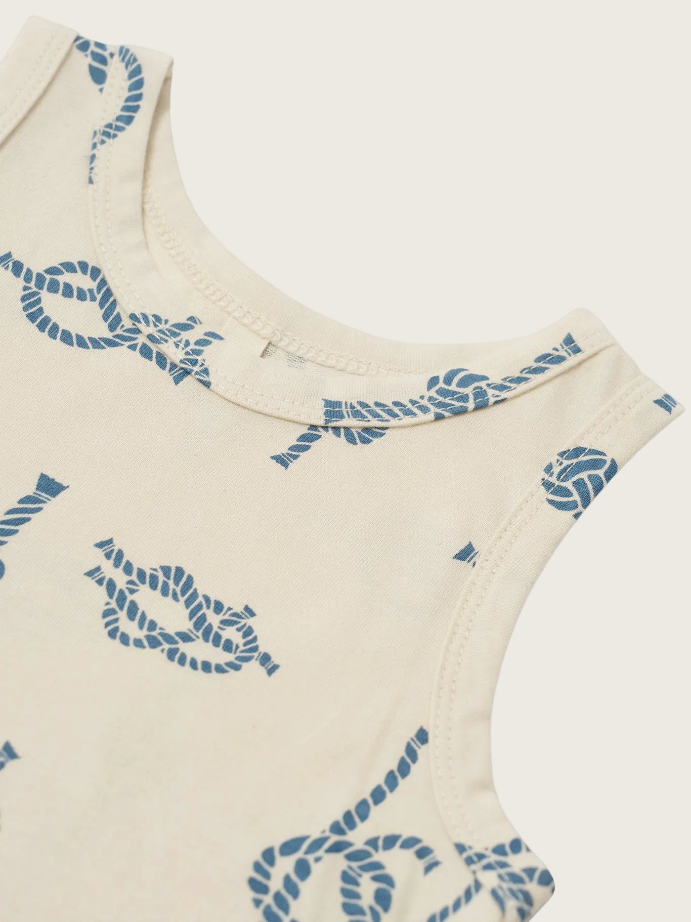 Beige sleeveless top with blue rope pattern on a white background