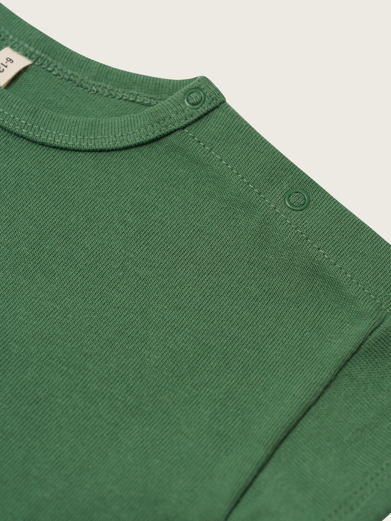 Close-up of a green long-sleeve shirt with a plain background