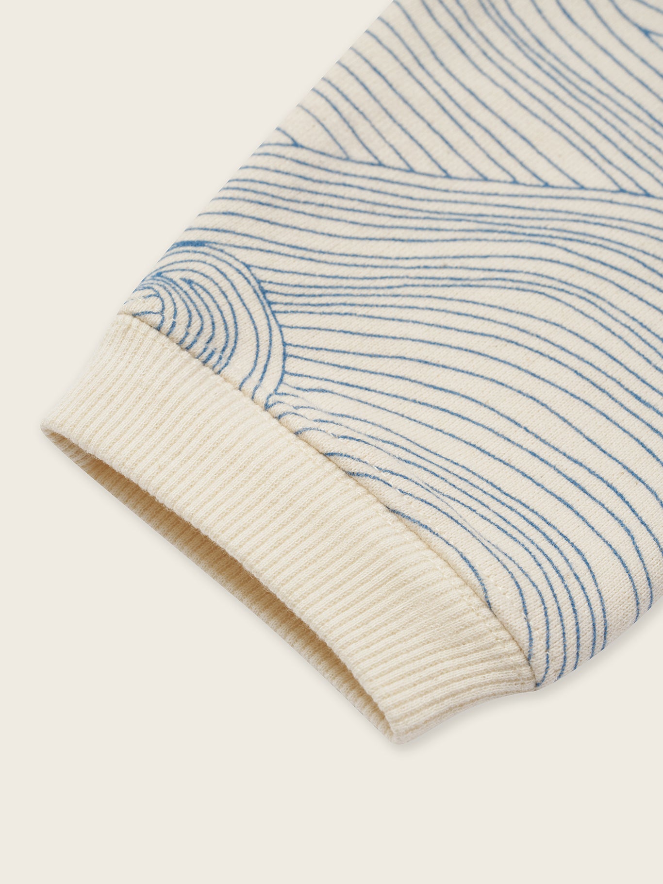 close up of cream undyed cotton sweatshirt with Seascape design of flowing blue line-drawn ocean waves