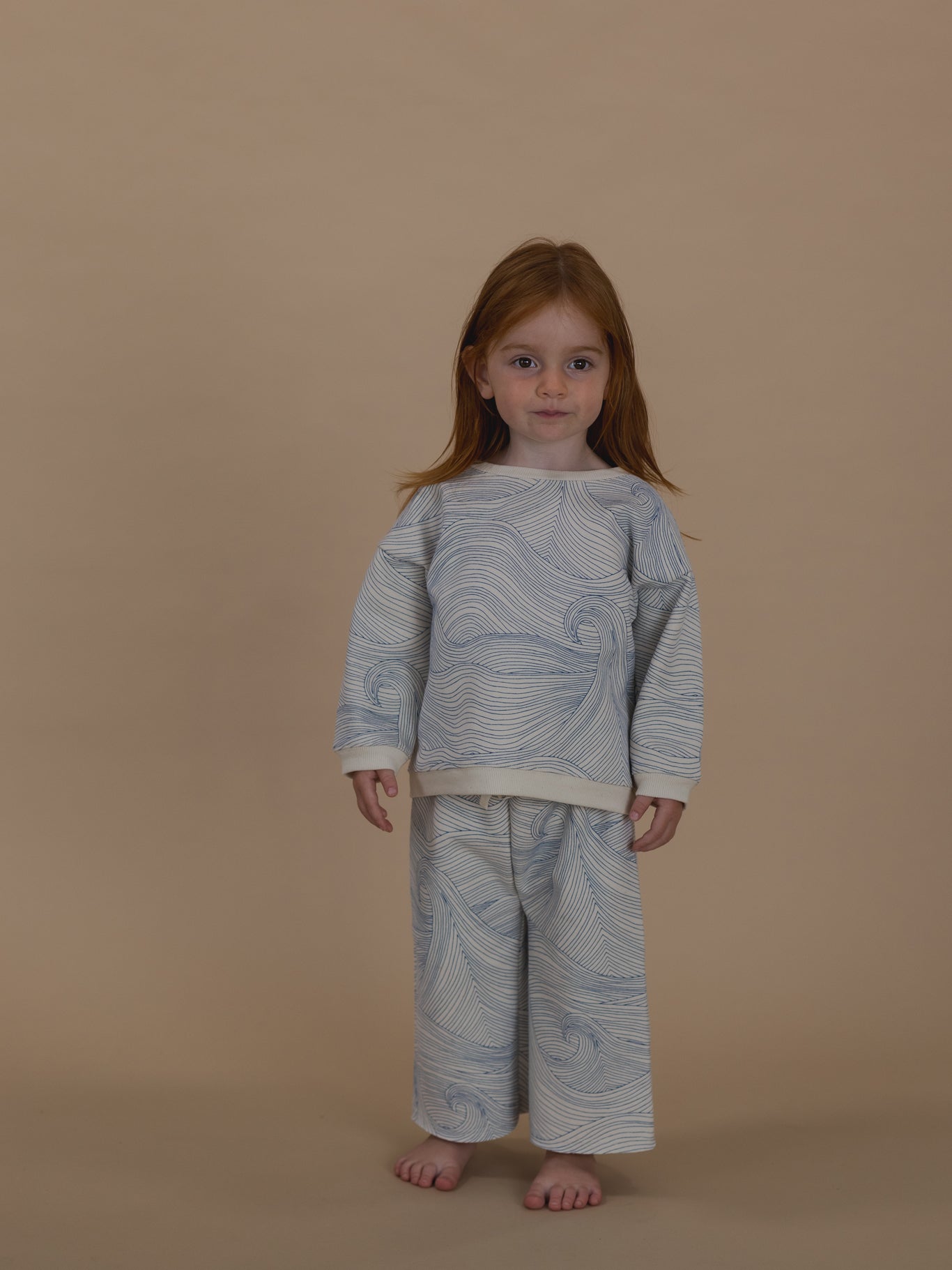 toddler in cream cotton sweatshirt with blue Seascape line-drawn ocean waves and matching pants